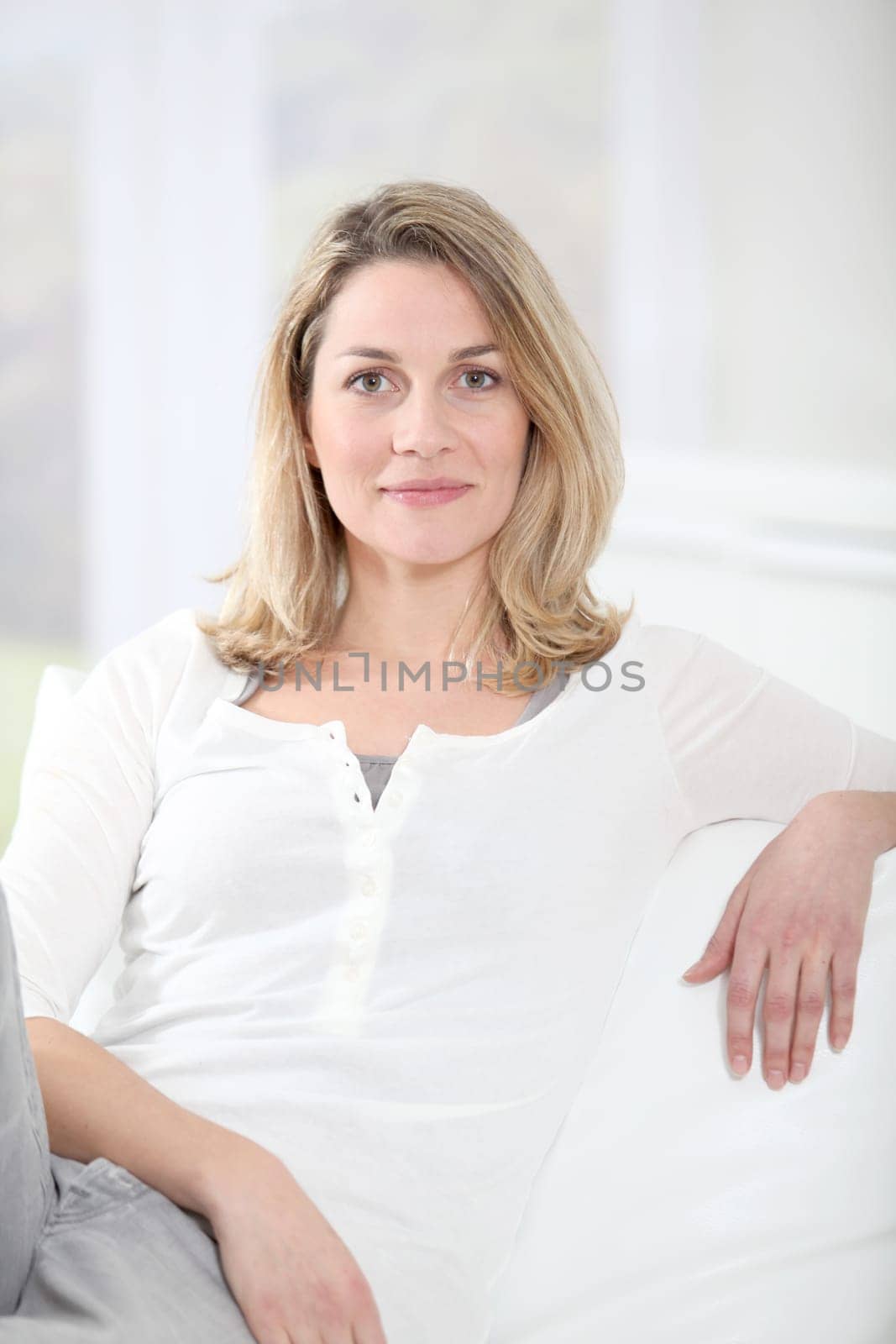 Portrait of beautiful blond woman sitting on sofa