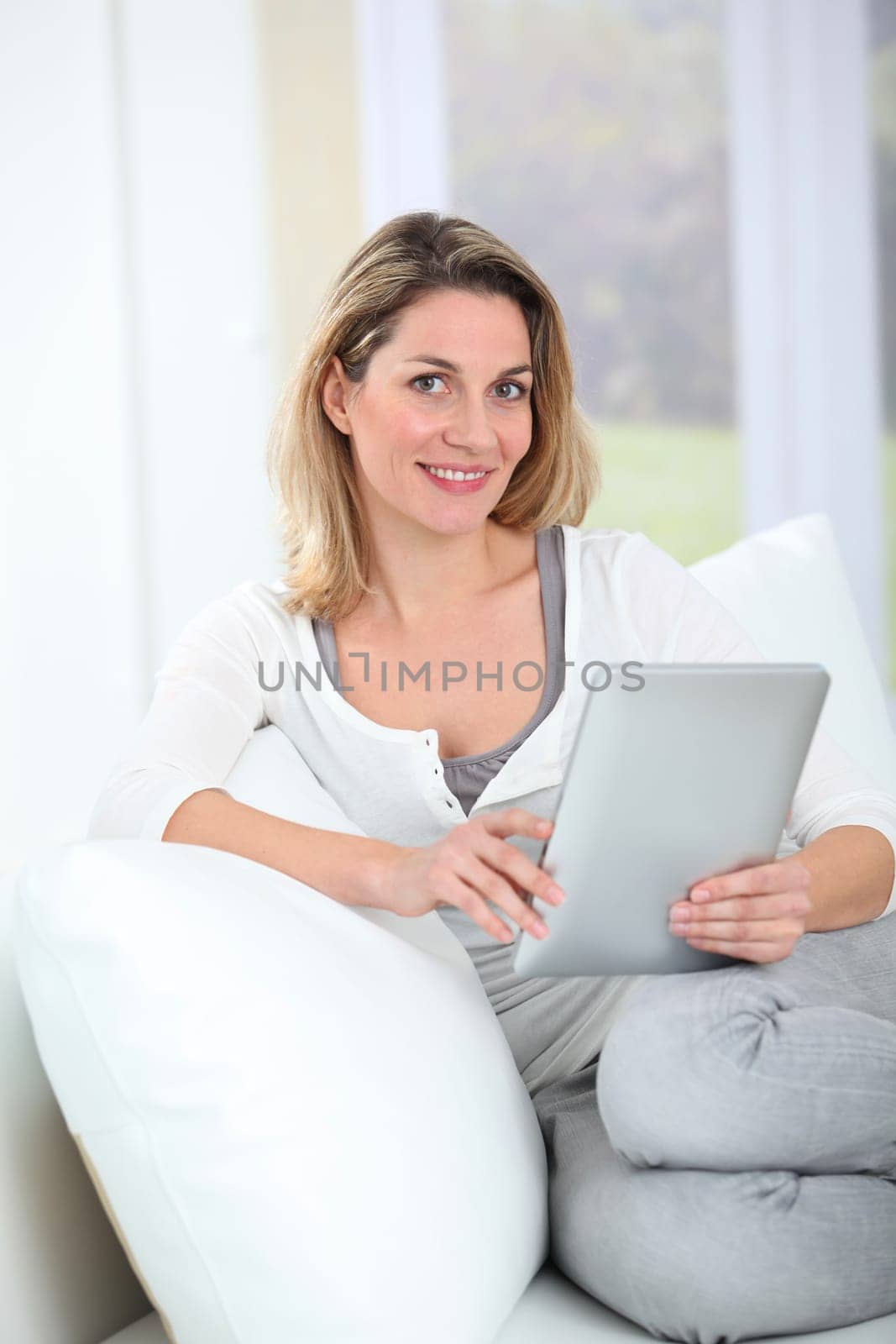 Woman using electronic tab sitting in couch
