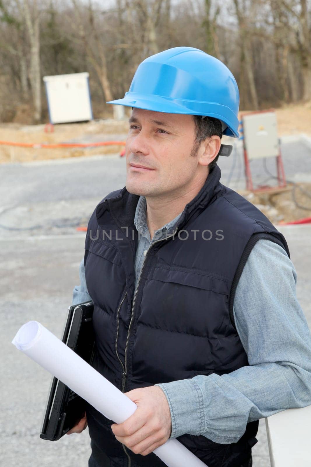 Site supervisor with security helmet standing on construction site