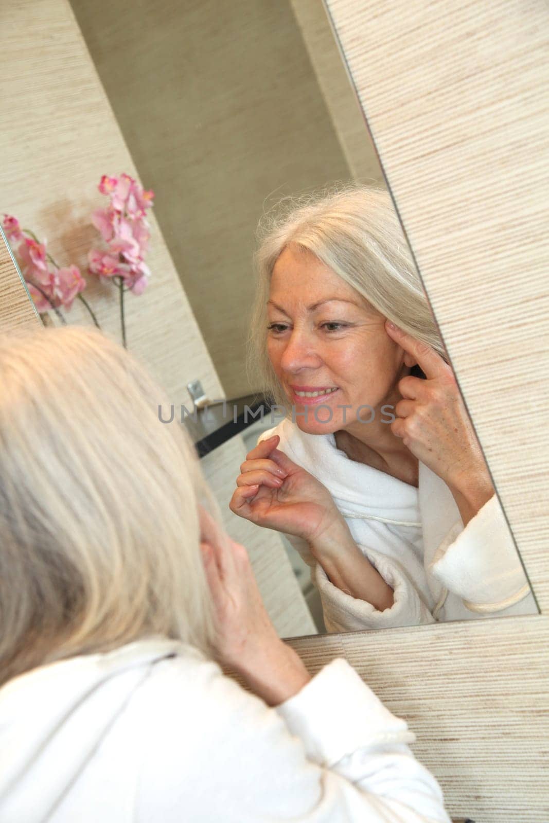 Senior woman applying moisturizer on her face