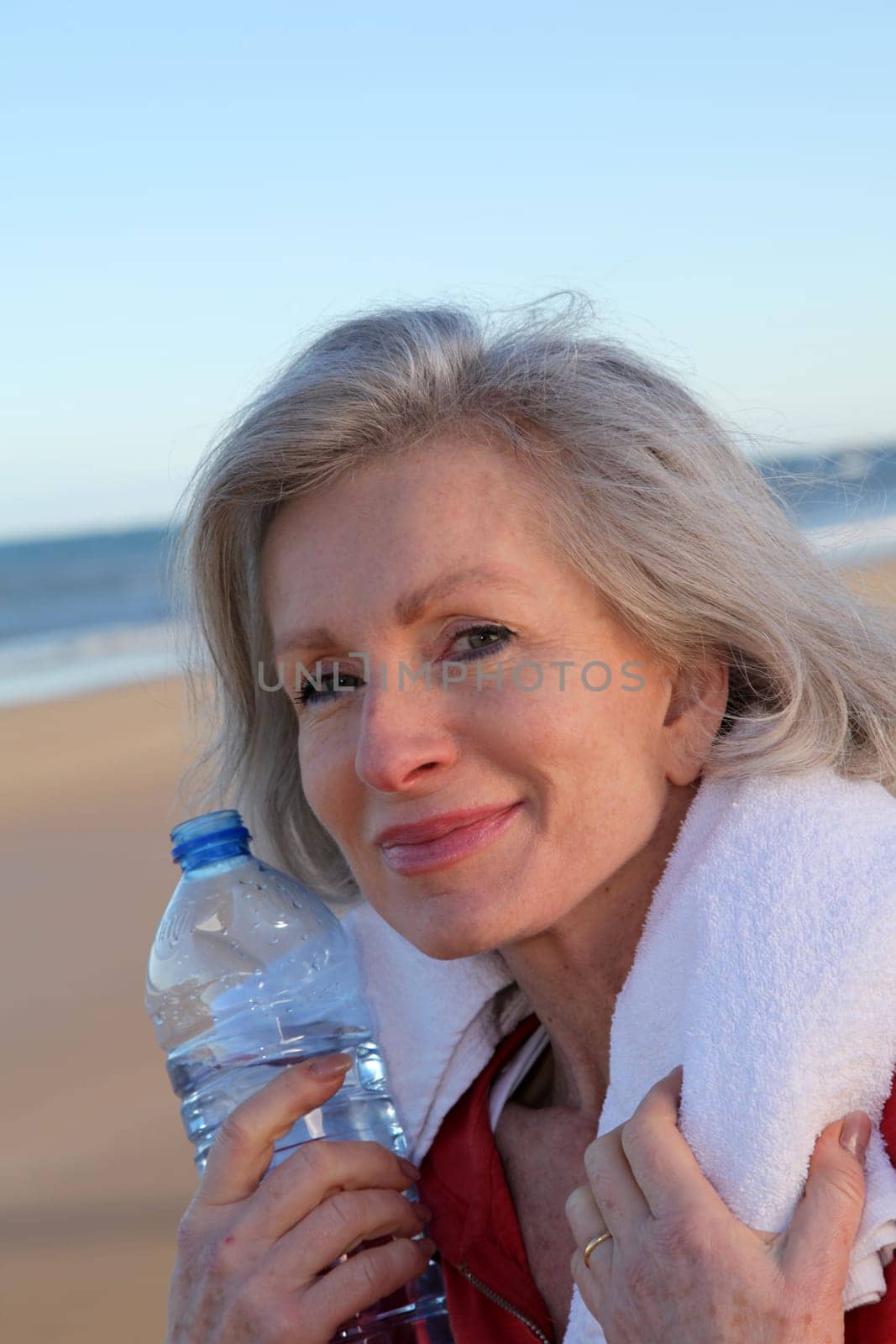 Active senior woman drinking water from bottle at the beach