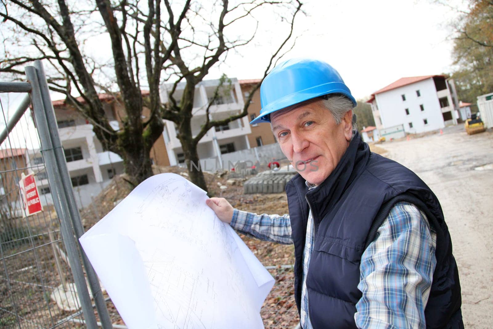 Architect with drawing on construction site