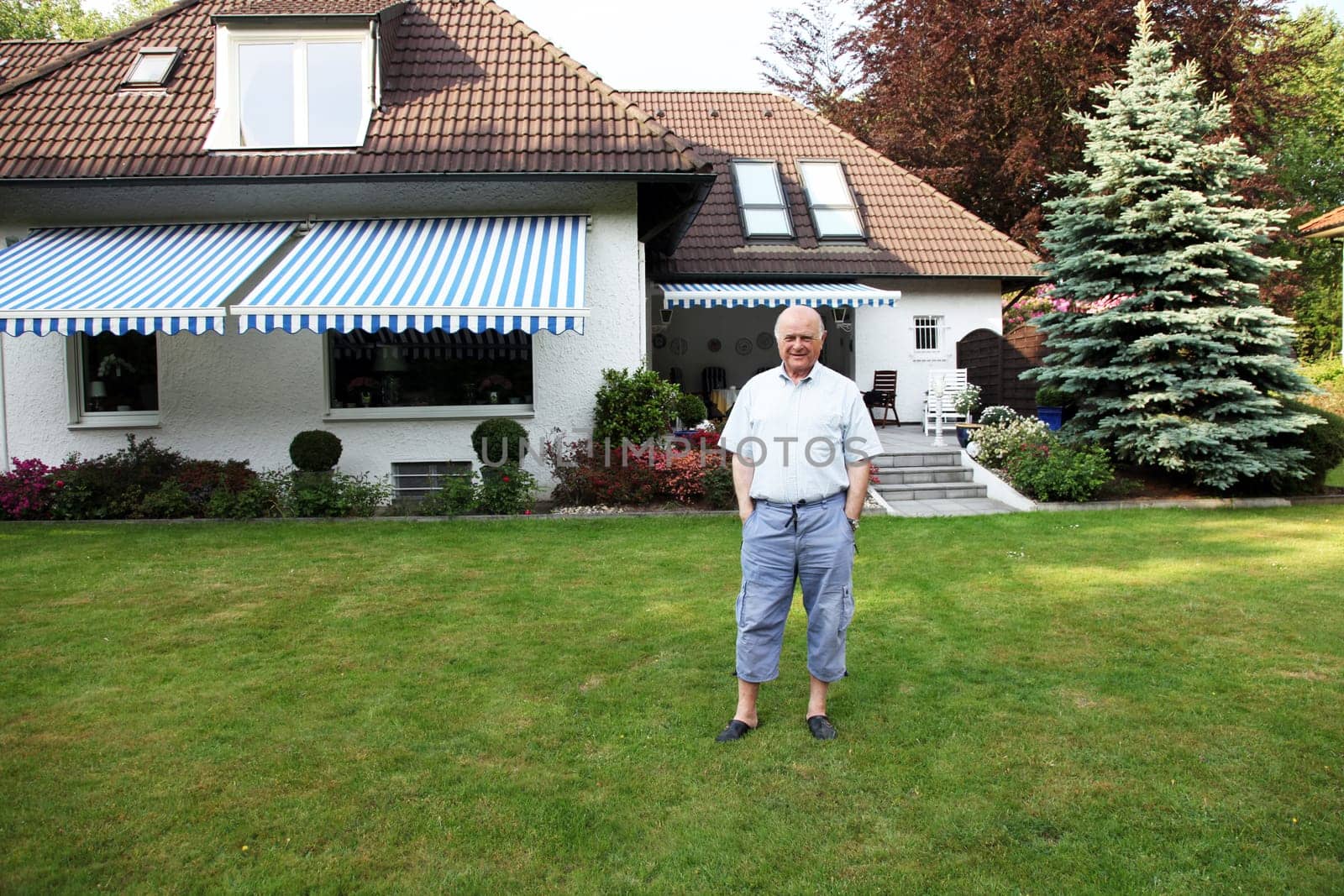 Friendly senior in front of his house in casual look