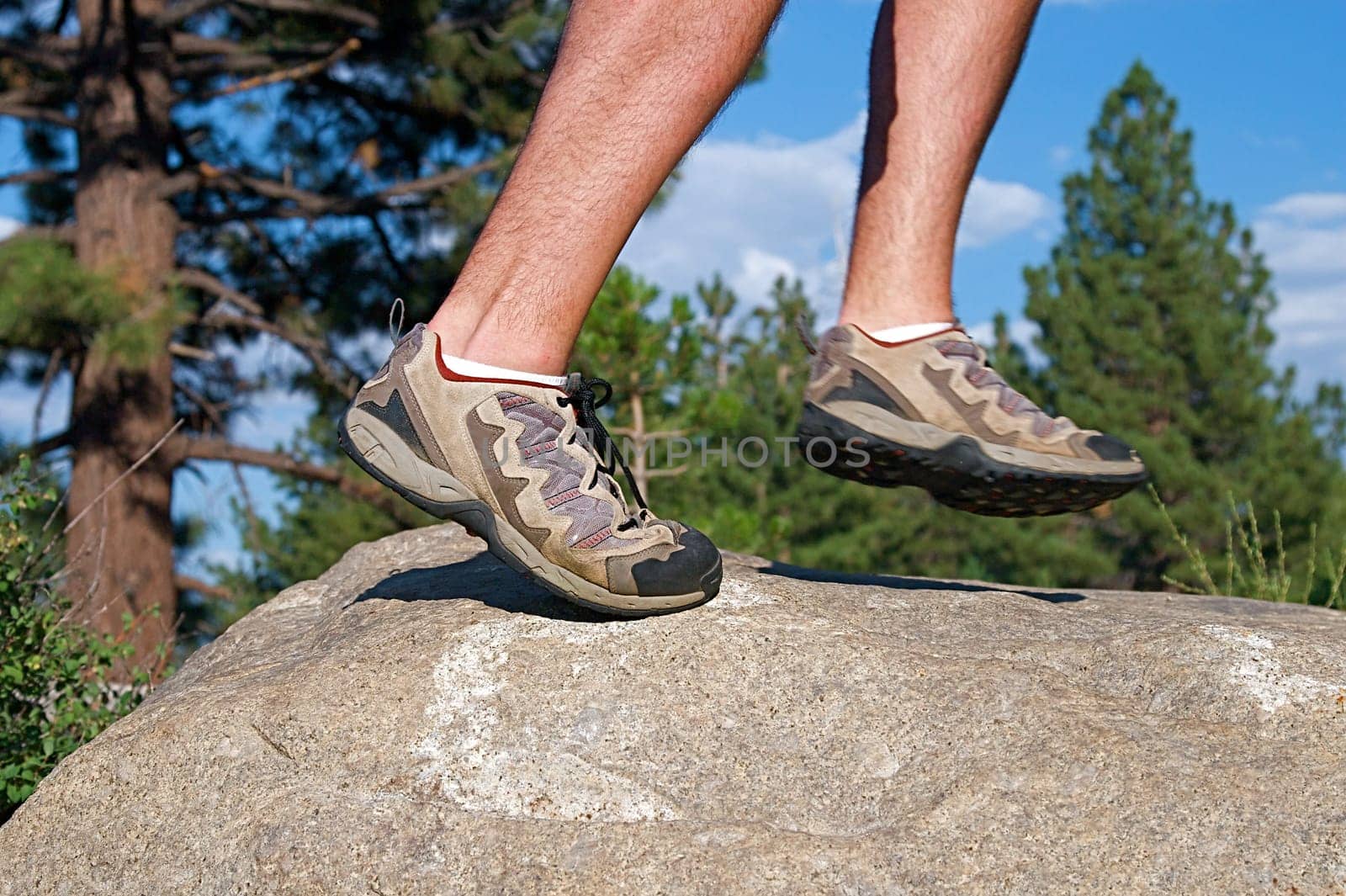 Trail runner climbing a steep rock in his path