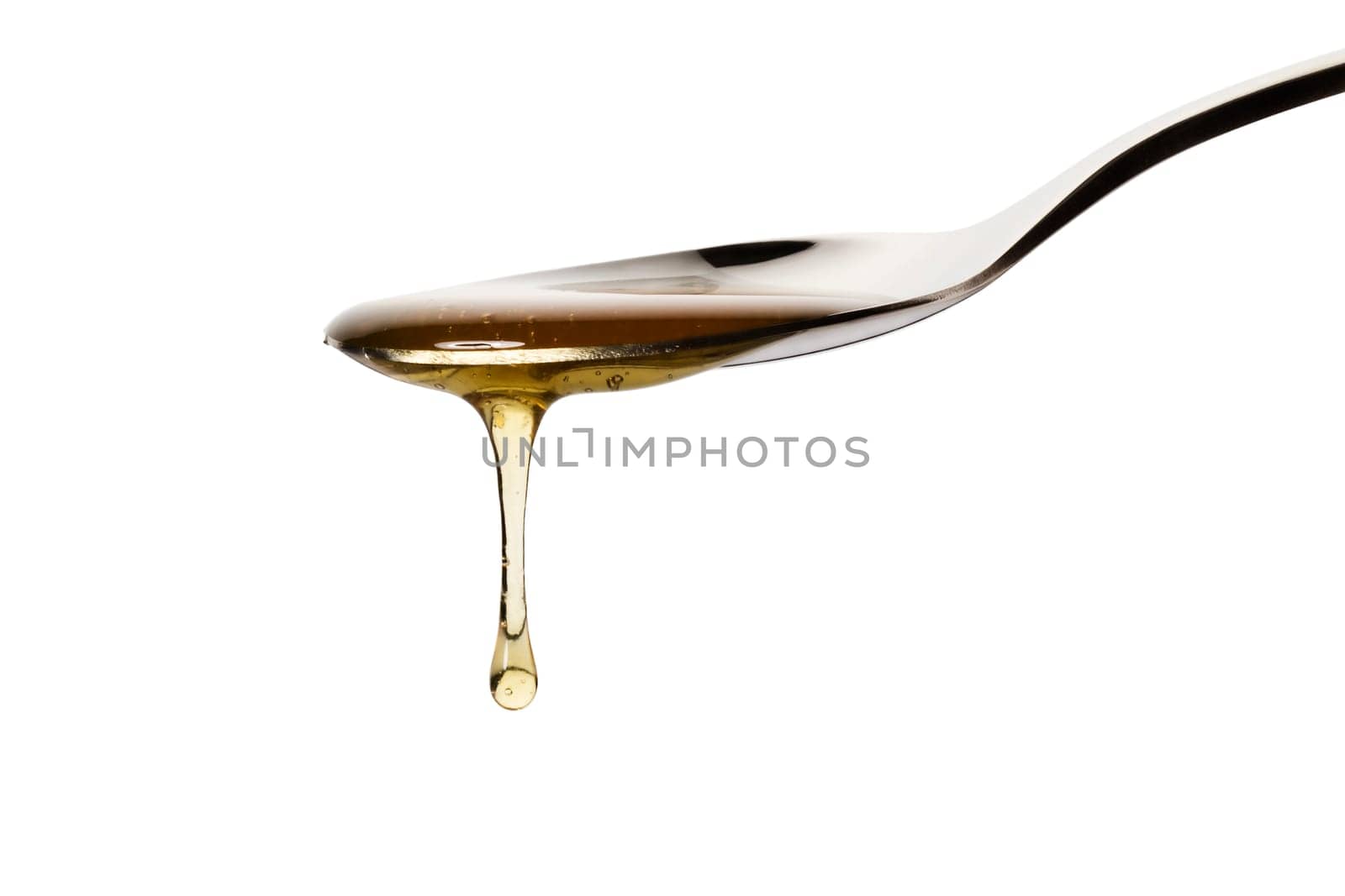 Honey dripping from a spoon against a white background
