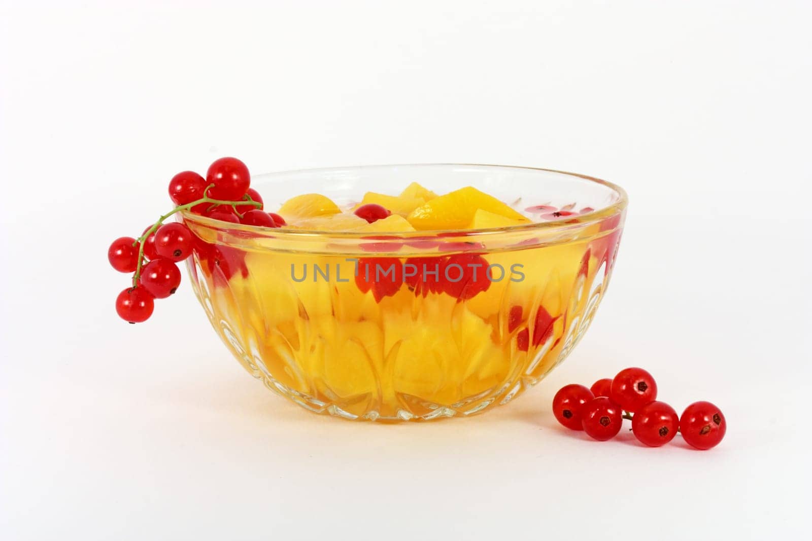 Peach compote with fresh red currants in glass bowl isolated on white