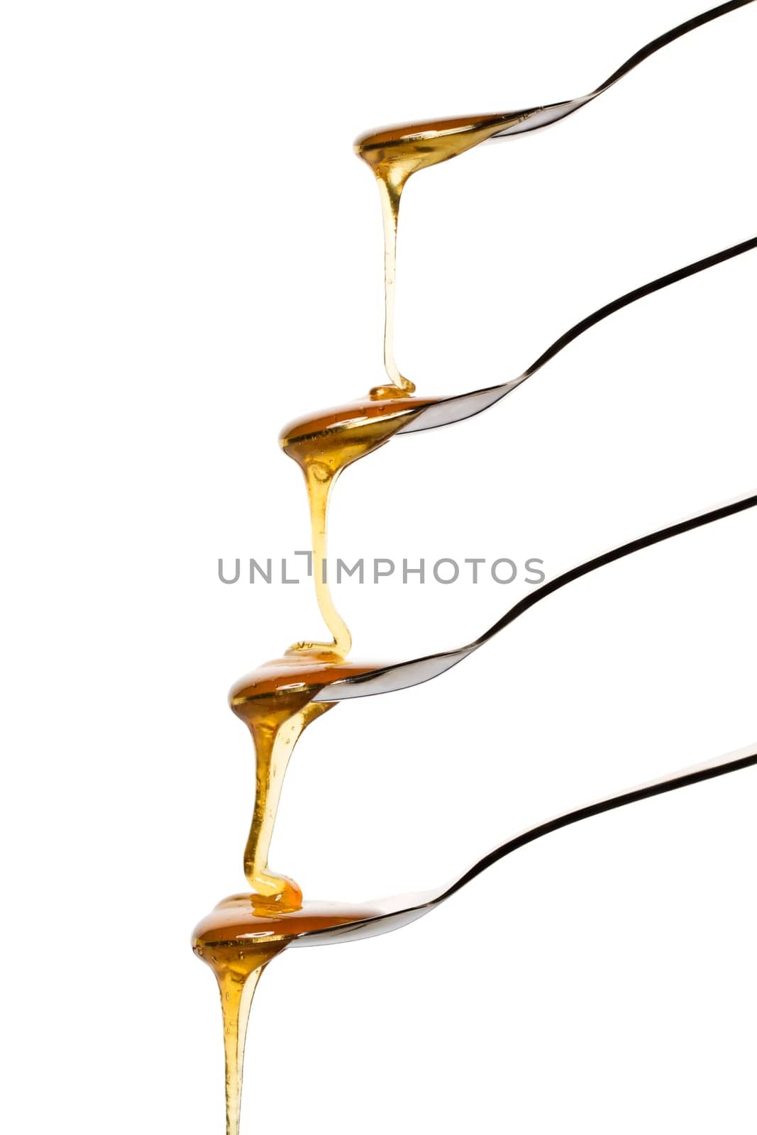 Honey flowing over four spoons against a white background