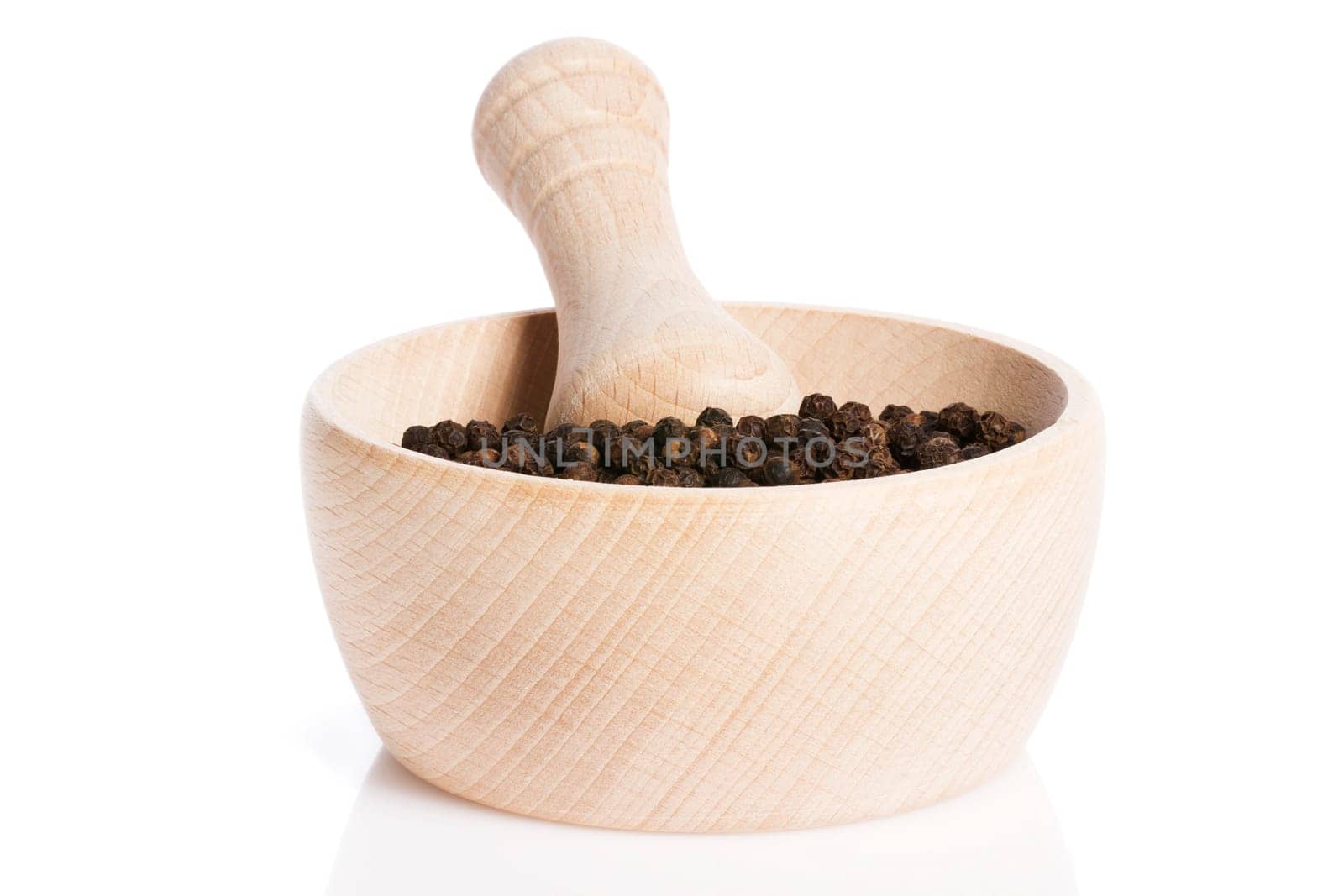 Peppercorns in a wooden mortar against a white background