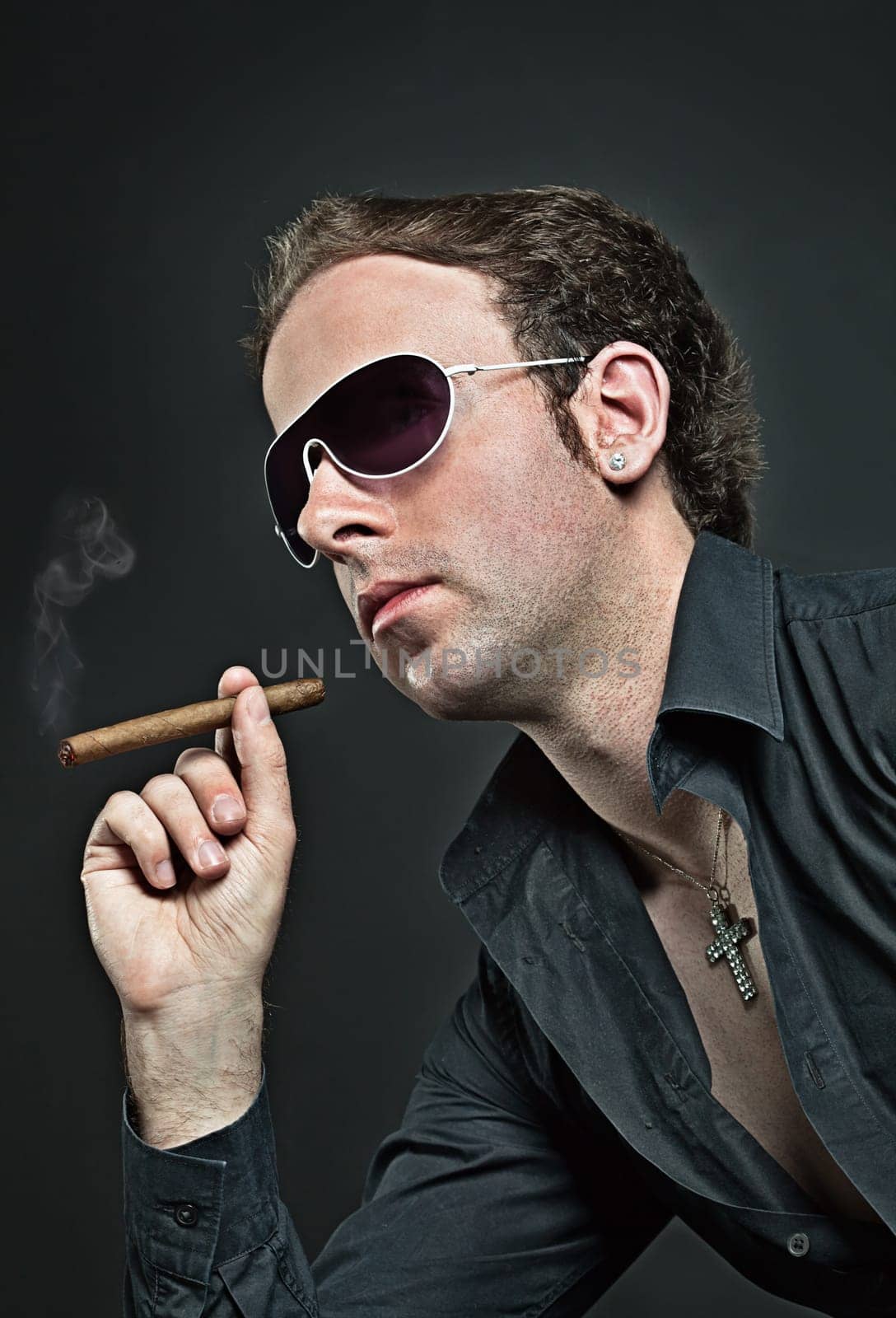Young cool guy in sunglasses smokes cigar