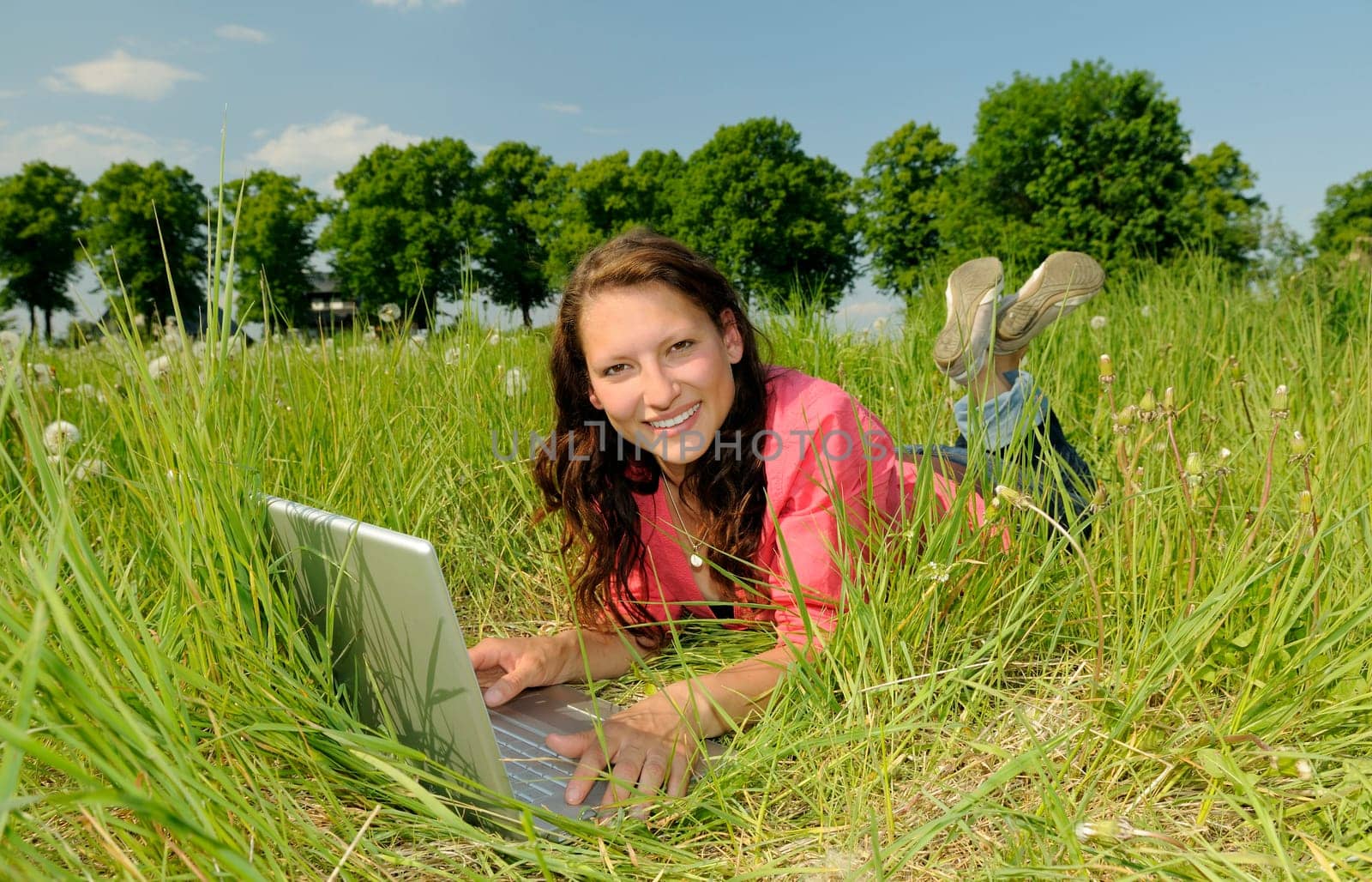 Young woman with laptop in a meadow