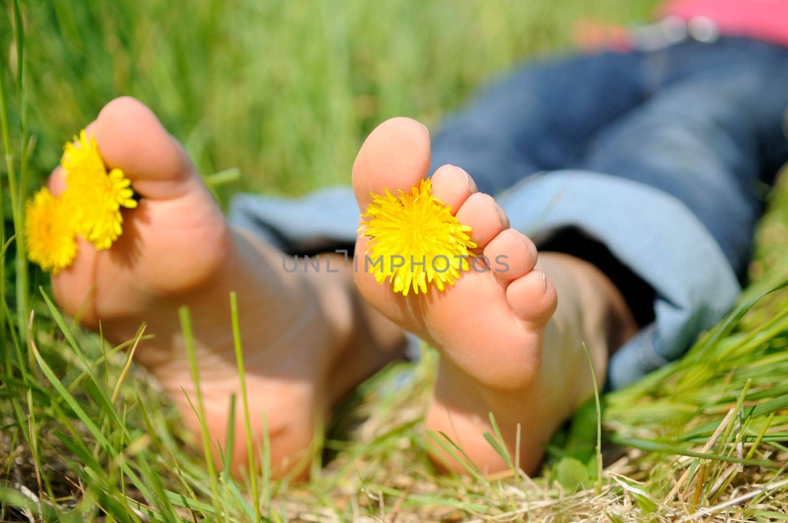 Young woman lying barefoot on a meadow