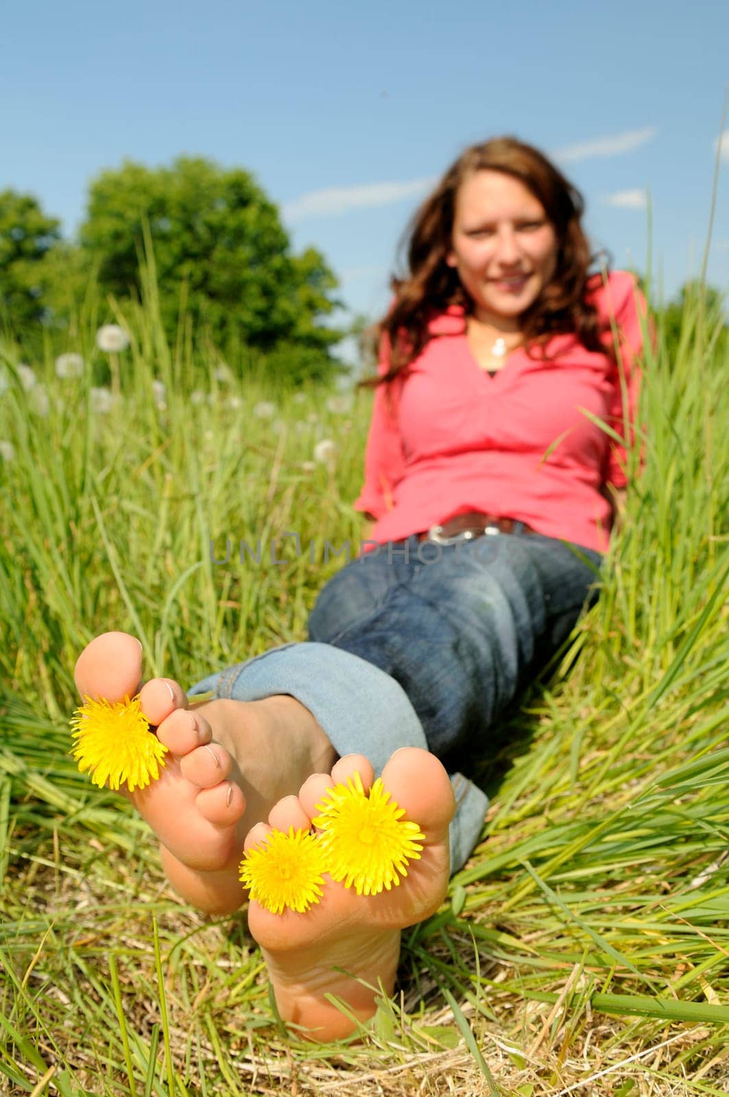 Young woman lying barefoot on a meadow
