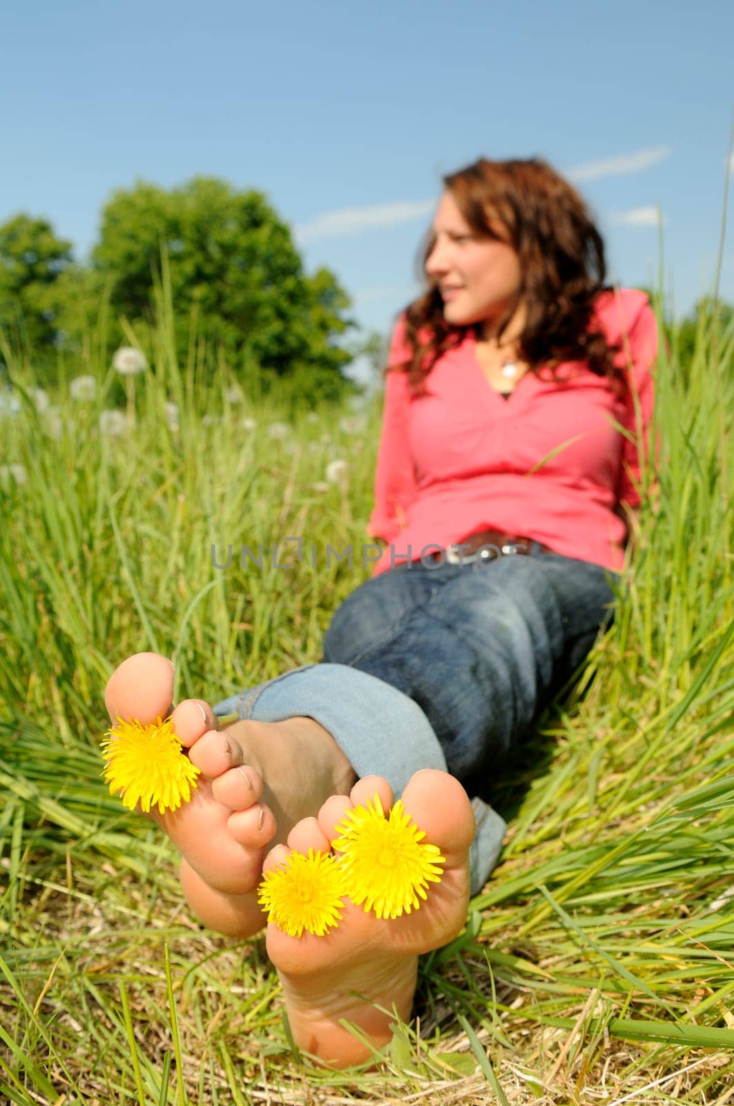 Young woman lying barefoot on a meadow