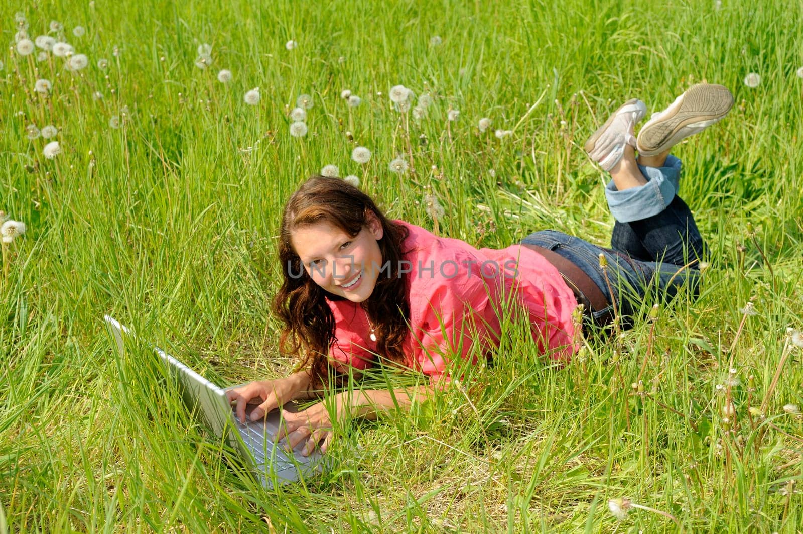 Young woman with laptop in a meadow