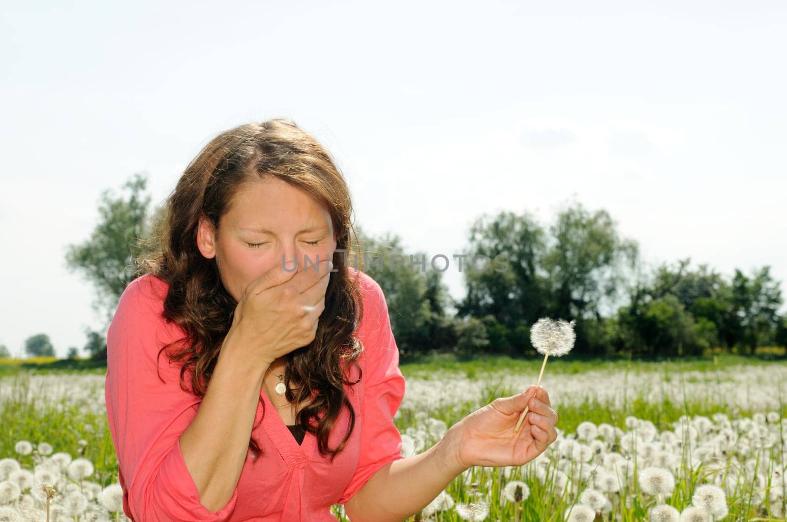 Young woman sneezing on a flower meadow