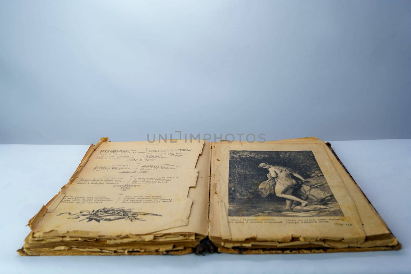 Open old book with fragile, yellowed pages and a vintage black-and-white illustration. Aged historical literature, perfect for themes of knowledge, history, and nostalgia