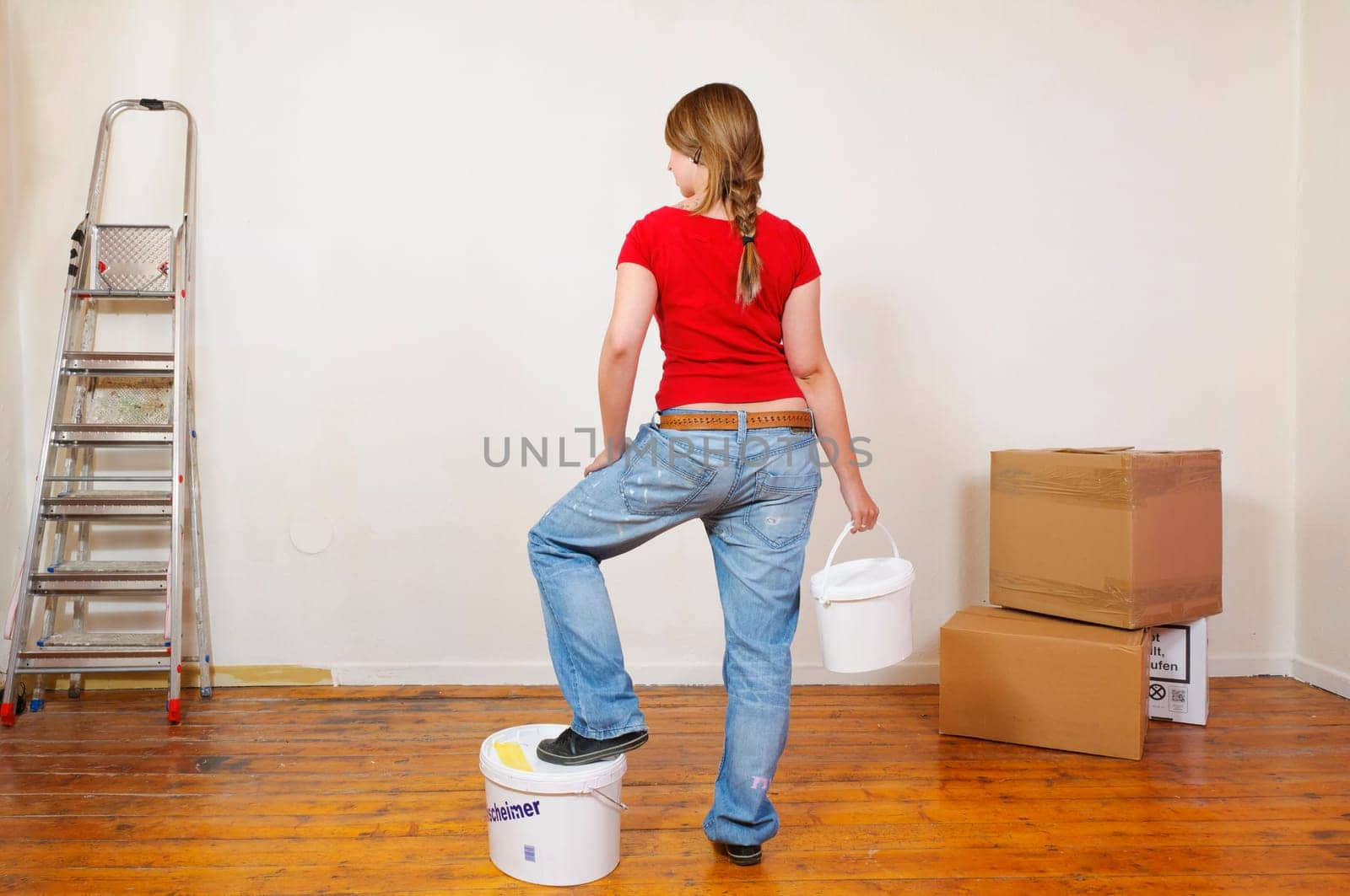 Young woman in a colorful T-shirt paints her first apartment with a paint roller.