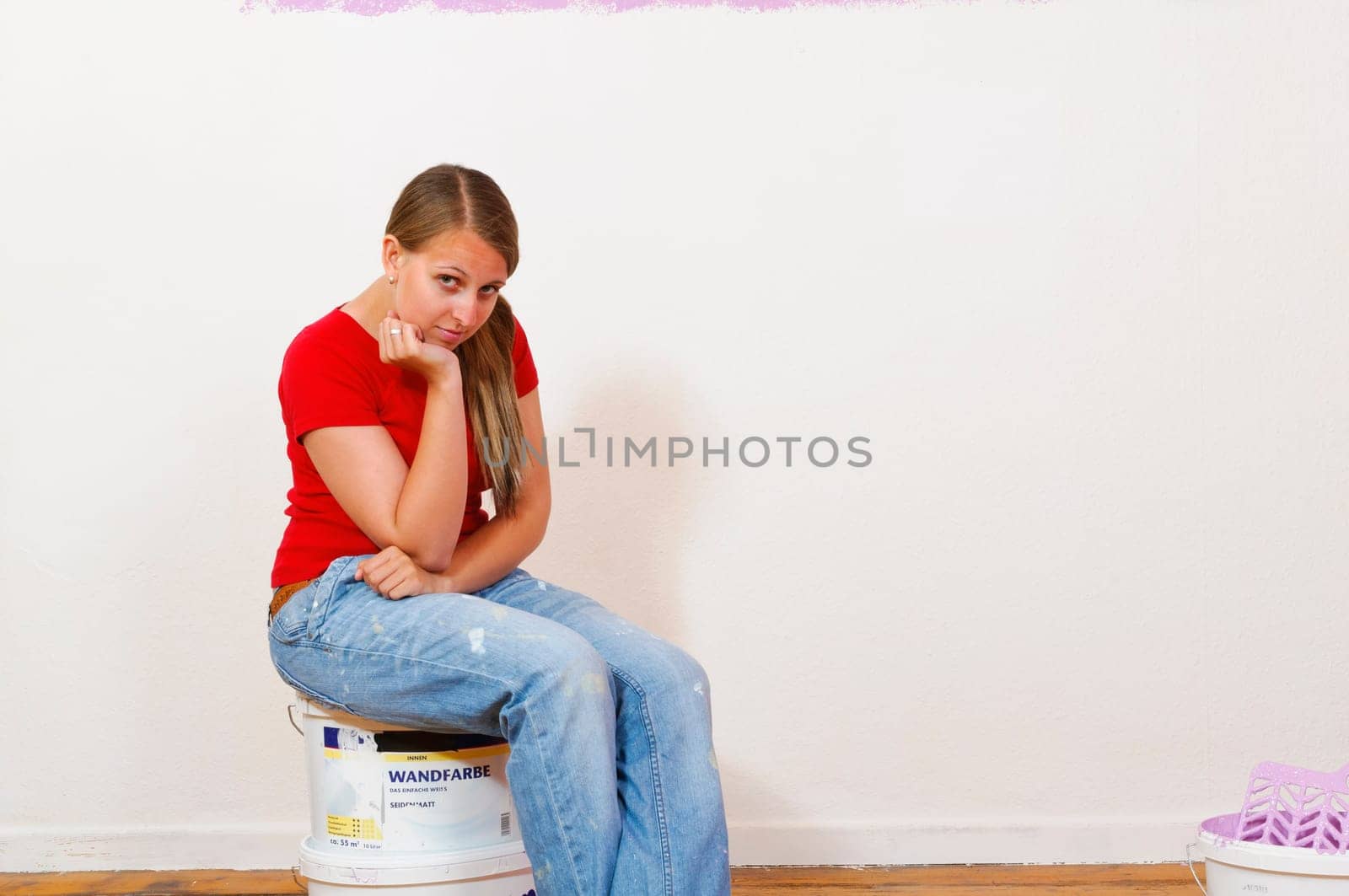 Young attractive woman with blond hair sweeps to the walls of their new home.