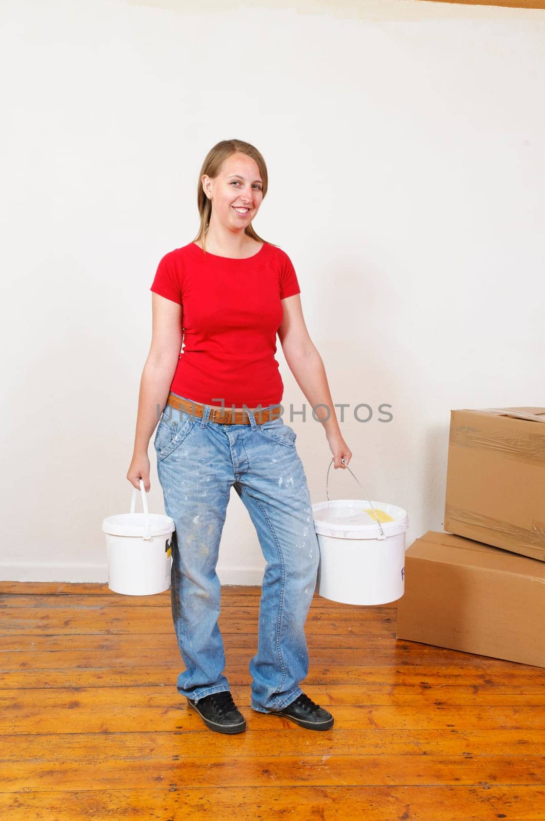 Young woman in a colorful T-shirt paints her first apartment with a paint roller.