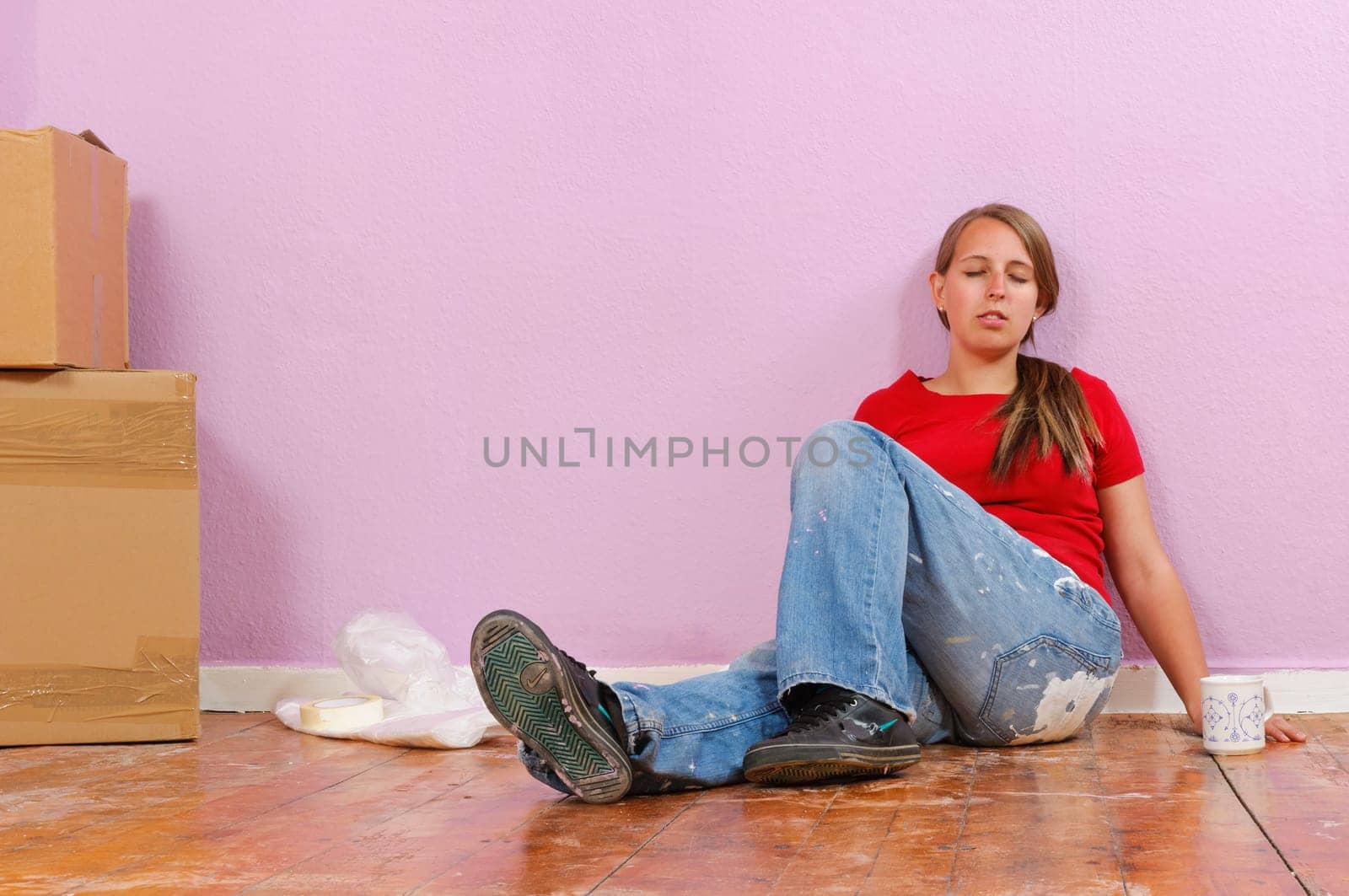 Young attractive woman with blond hair sweeps to the walls of their new home.