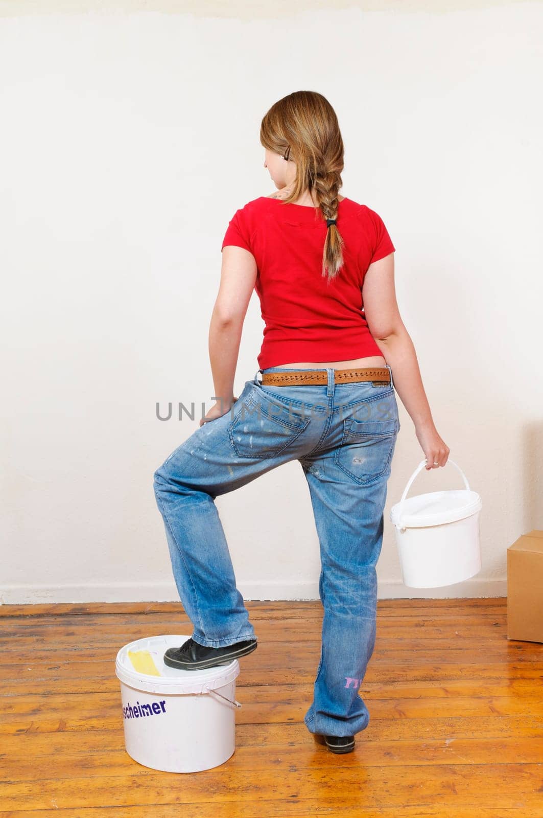 Young woman in a colorful T-shirt paints her first apartment with a paint roller.