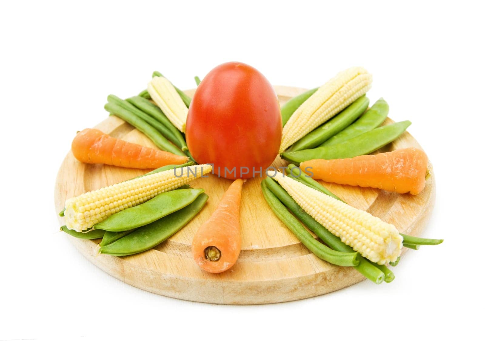 Healthy cooking with fresh vegetables - baby carrots, corn, beans and tomato on wooden chopping board. Isolated over white.