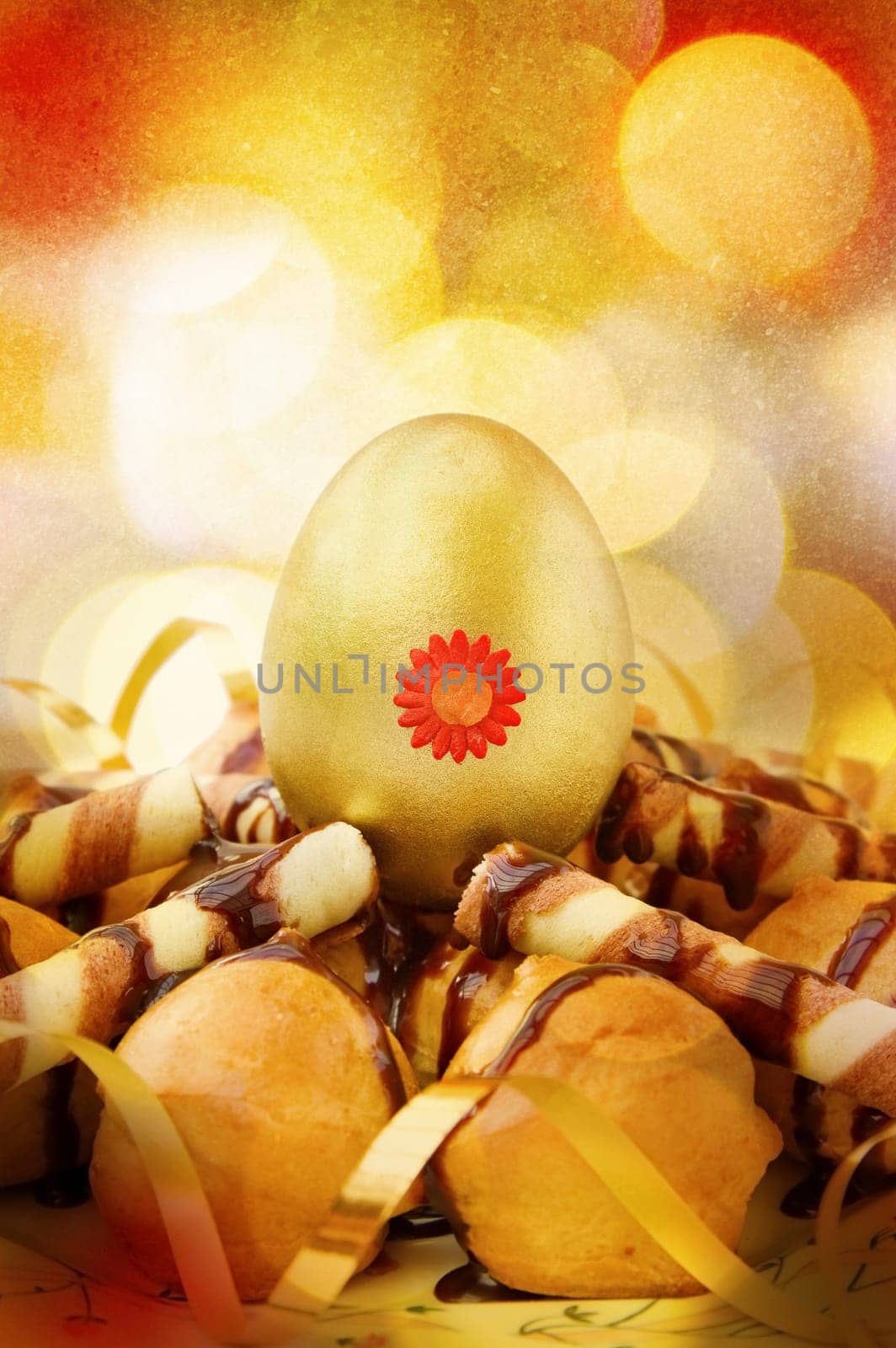 Celebrating Easter with decorated golden egg and chocolate profiteroles. Over festive bokeh lights.