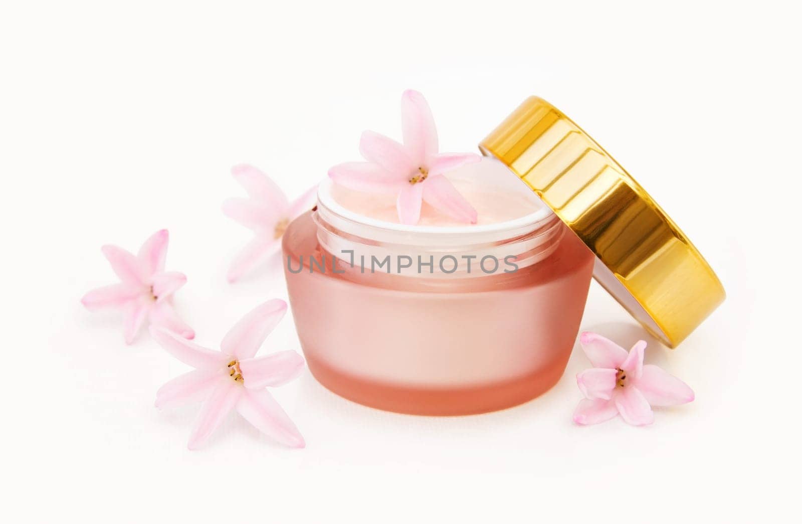 Luxury moisturizing face lotion with natural ingredients and fresh pink flowers. Isolated over white background.
