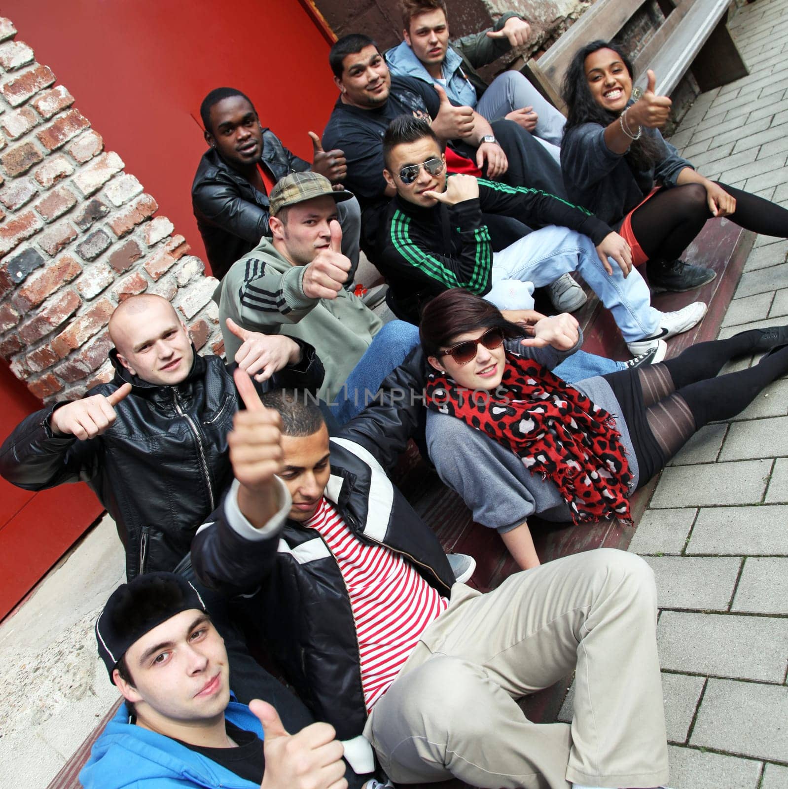 Ten young people sit together and give the thumbs up.  The group consists of boys and girls.
