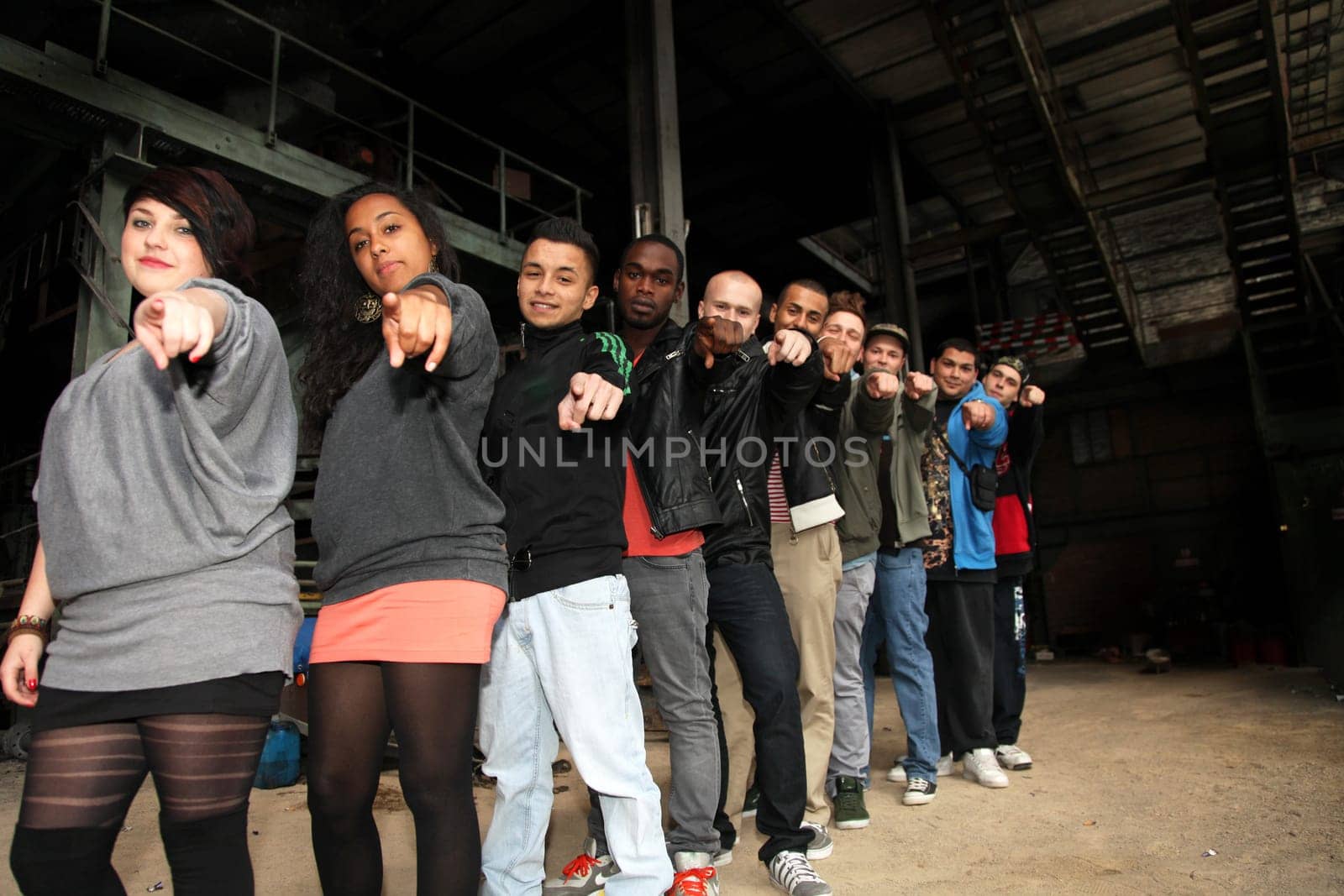 Ten cheerful teenagers of different nationalities in a row pointing towards the camera