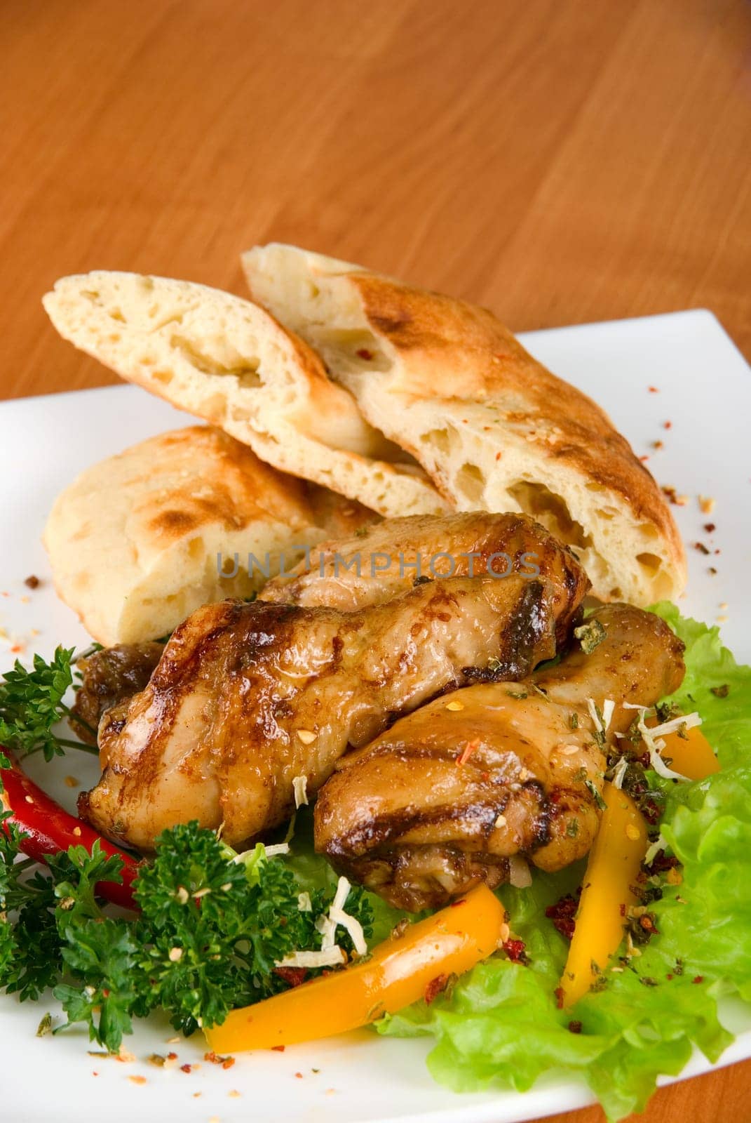 roasted chicken drumstick garnished with fresh green salad, pepper and greens