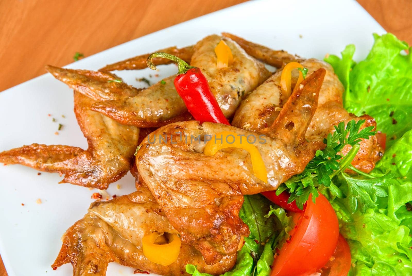 roasted chicken wings garnished with fresh green salad, pepper and greens