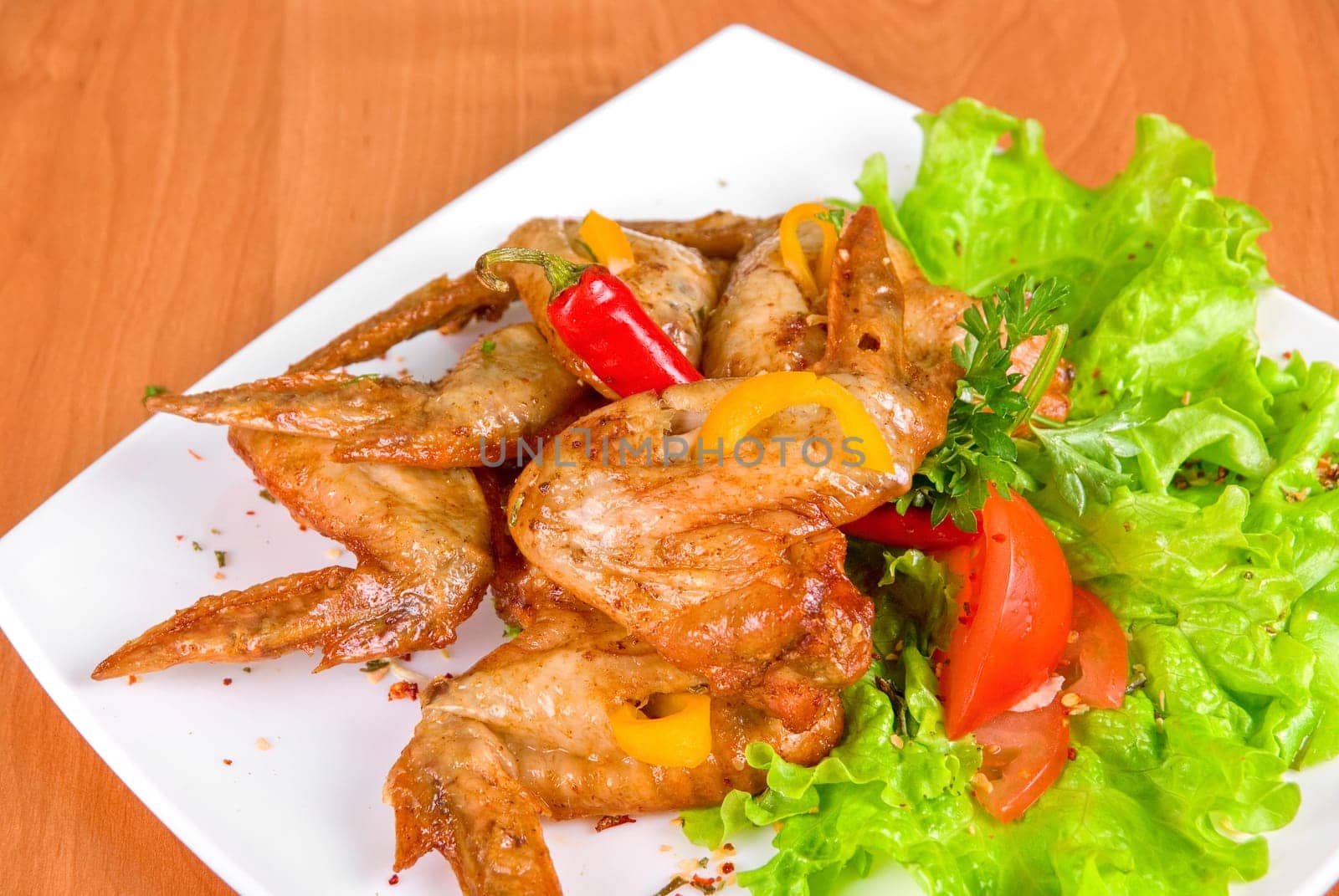 roasted chicken wings garnished with fresh green salad, pepper and greens