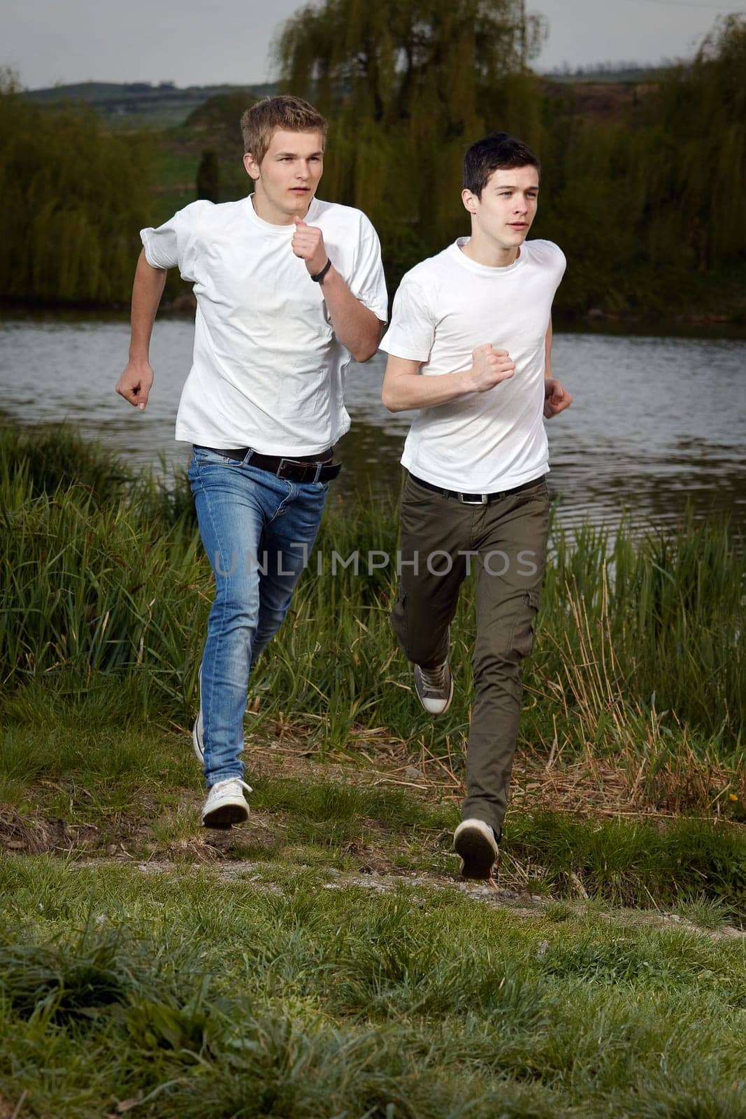 Fit men jogging outdoors beside the lake park