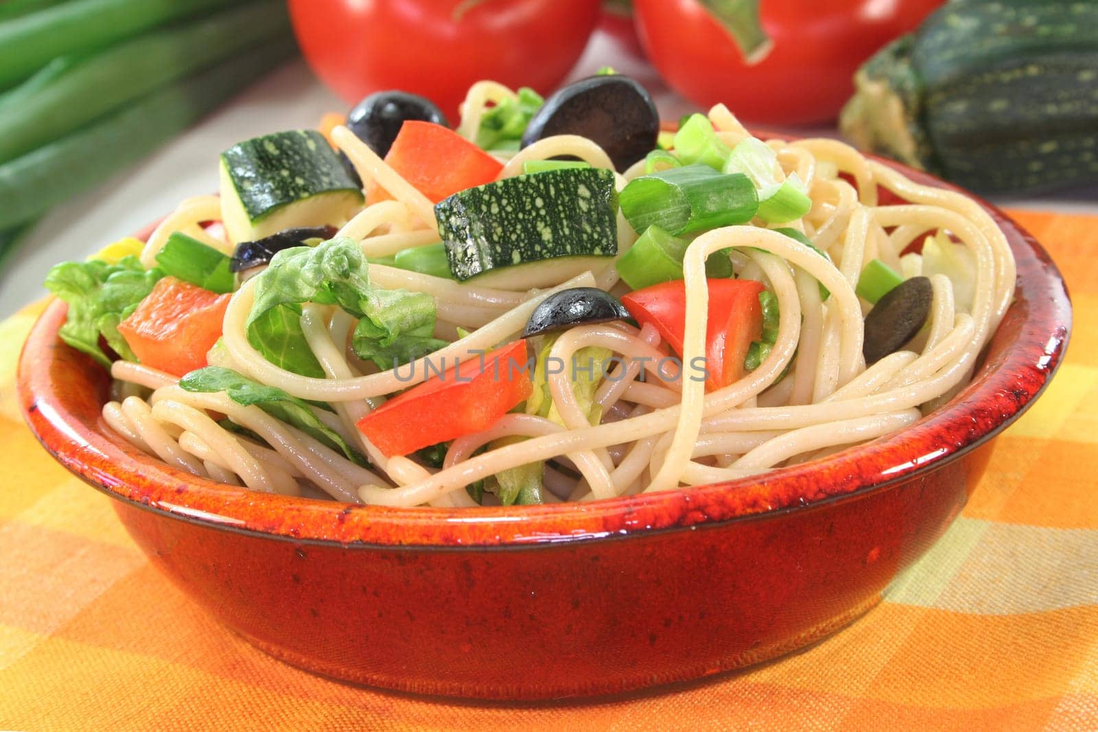 a bowl of pasta salad with spaghetti and fresh vegetables