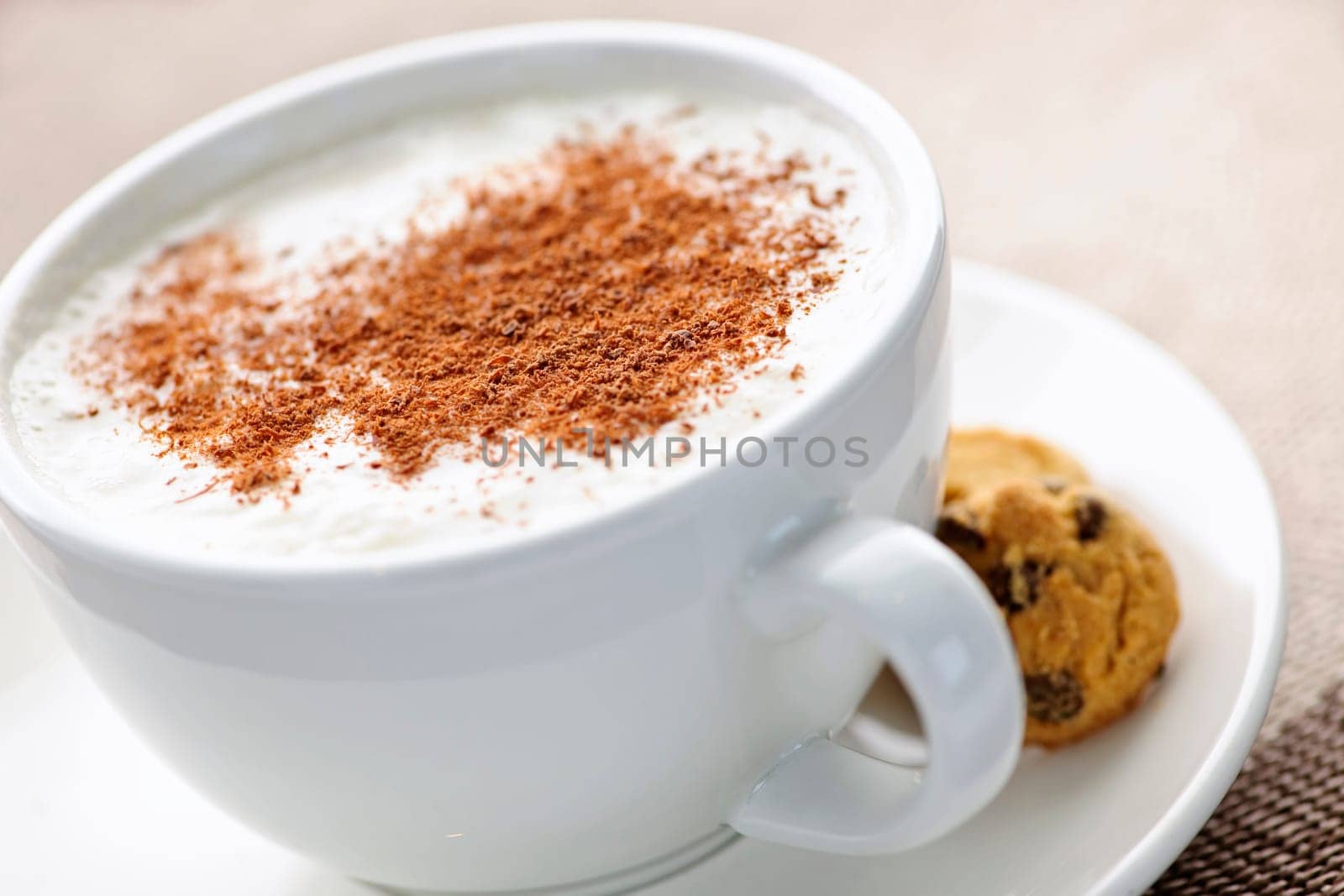 Cappuccino or latte coffee in cup with frothed milk and cookies