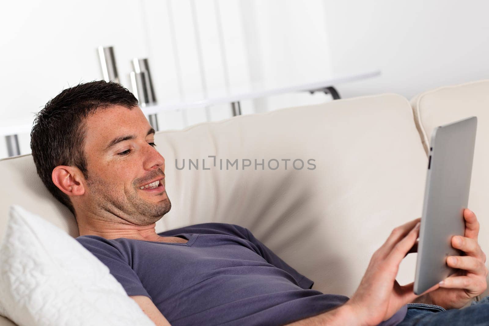 man using tablet pc on sofa at home