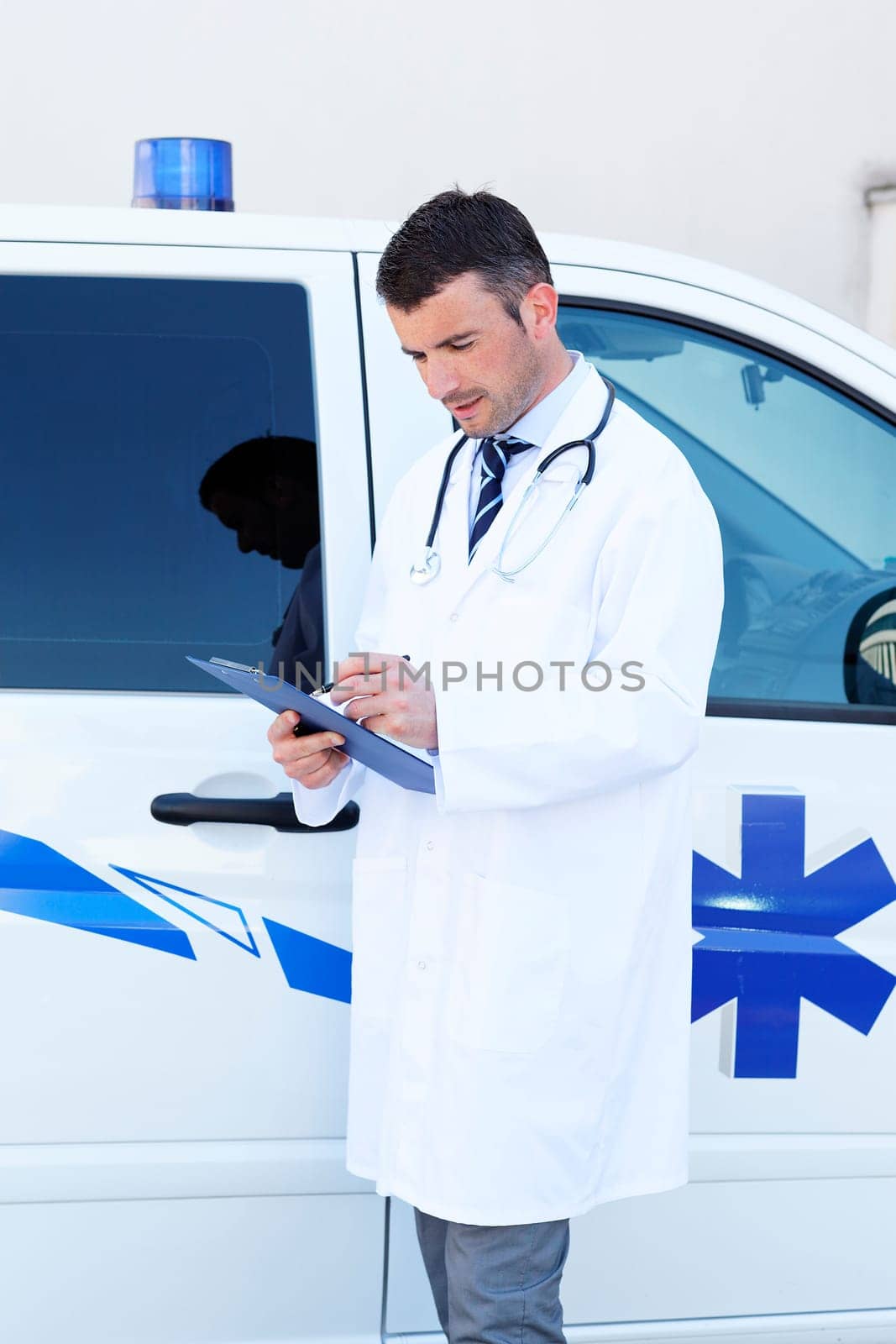 young doctor writing in front of ambulance