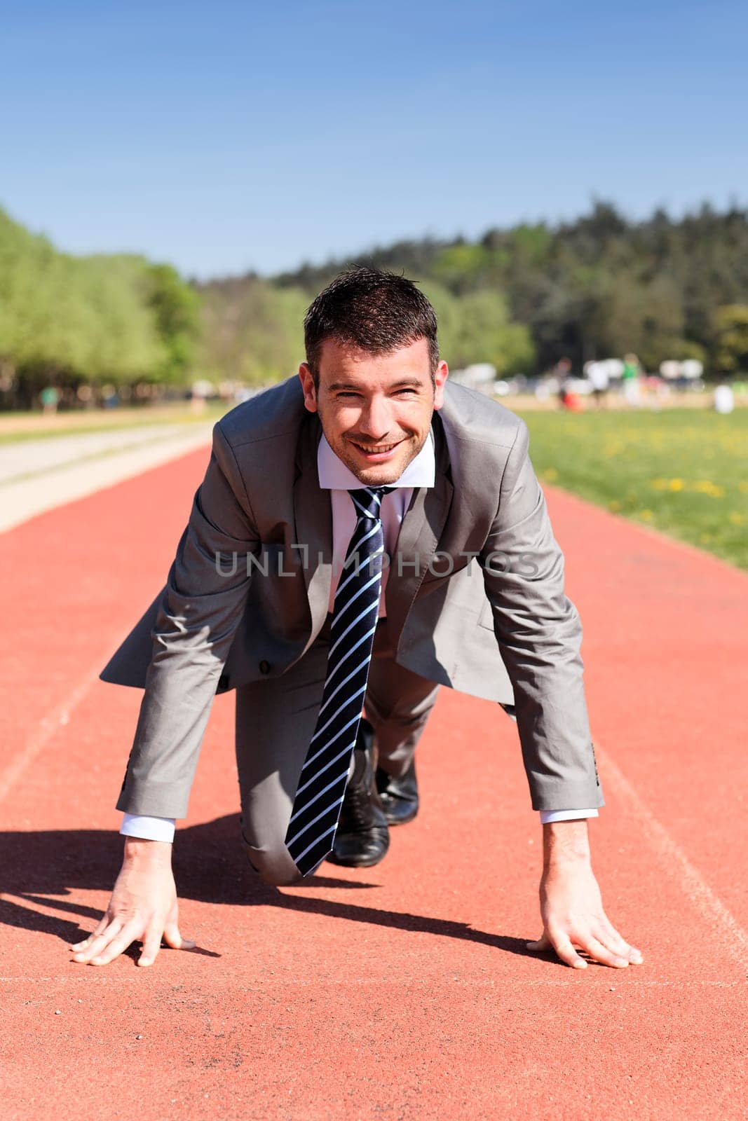 young businessman on a running track in summer