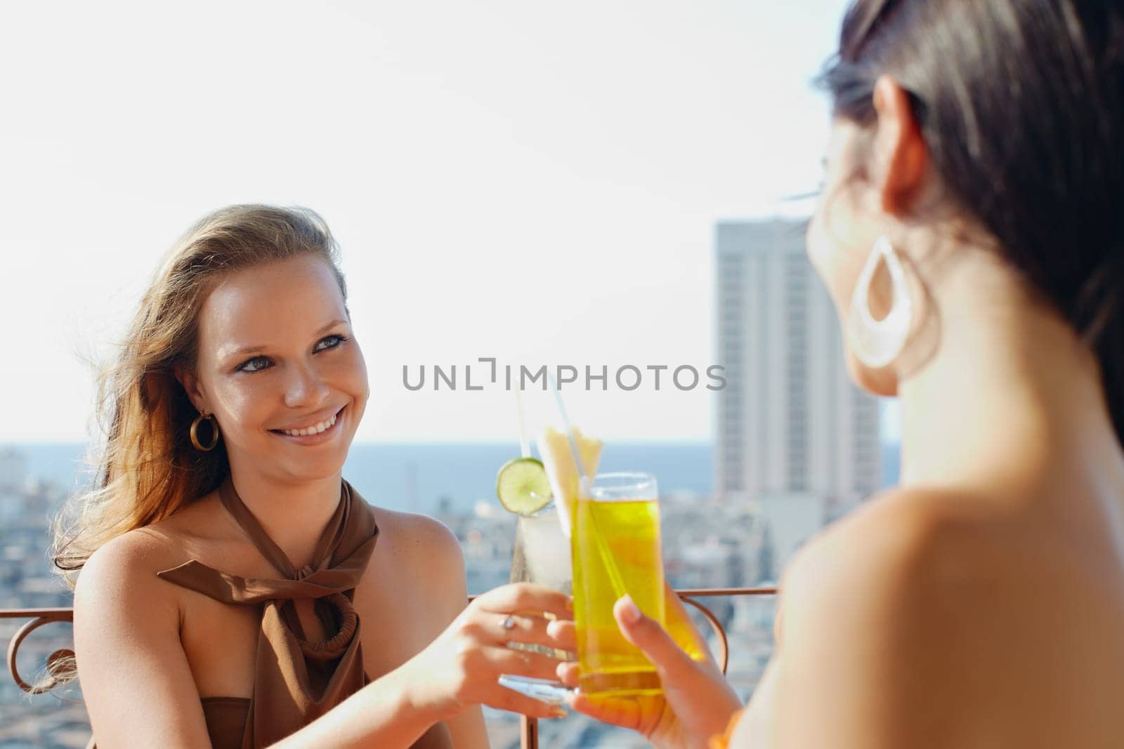 young caucasian female couple drinking cocktails and smiling on terrace in Havana, Cuba. Horizontal shape, waist up, copy space