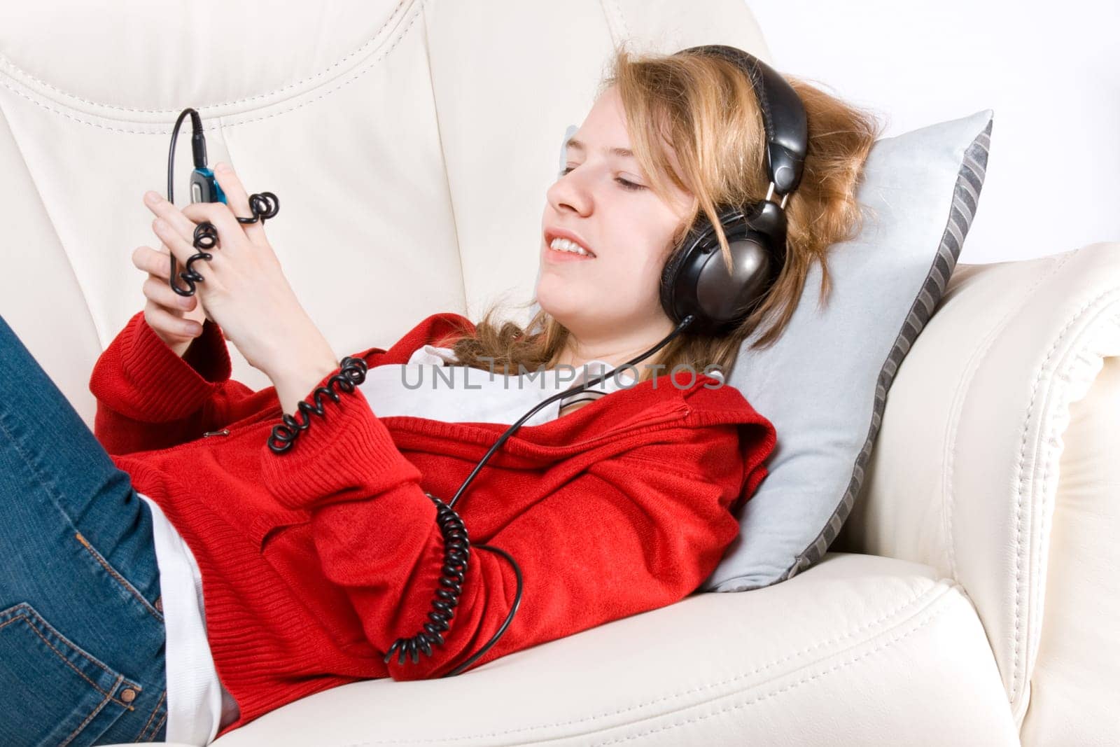 Young woman listening to music from cellphone lying on coach