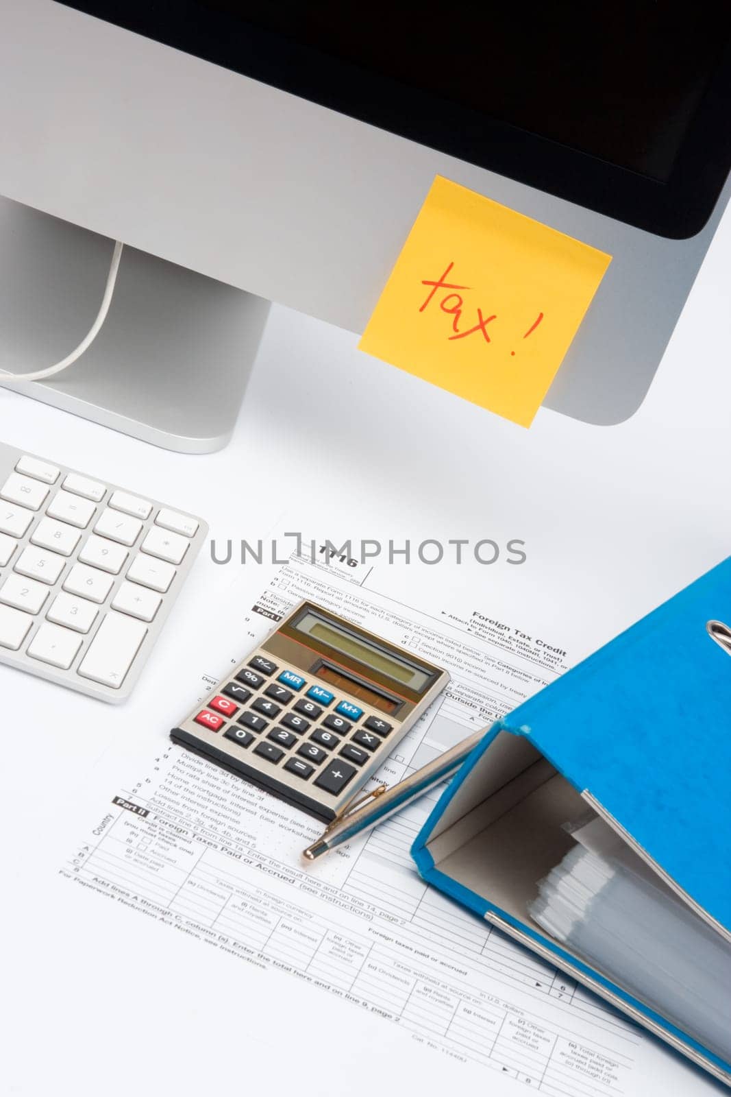 Tax concept - sticky notes with word tax, tax form, part of computer, keyboard, calculator, office folder and pen