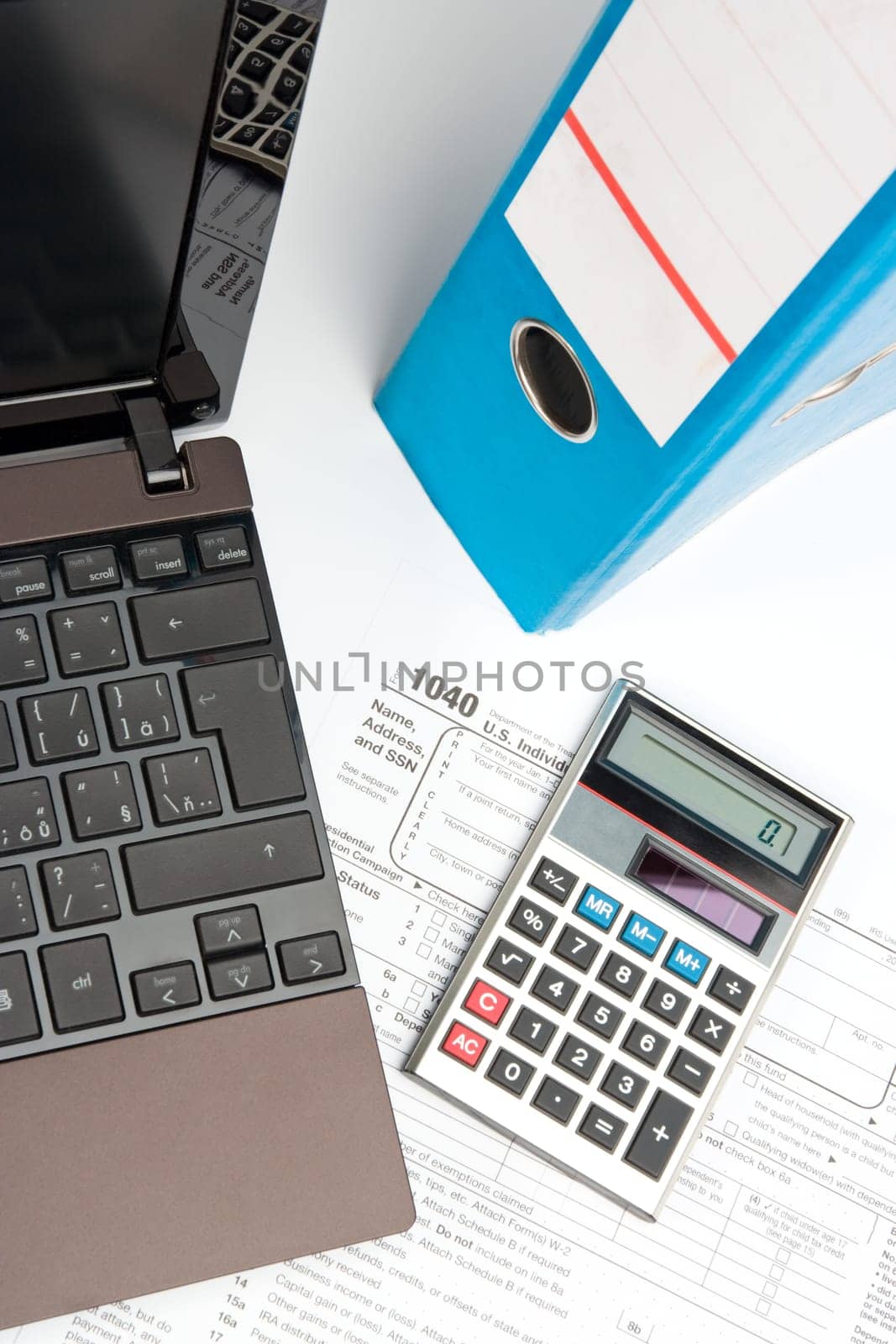 Tax form, part of laptop, calculator, office folder and pen