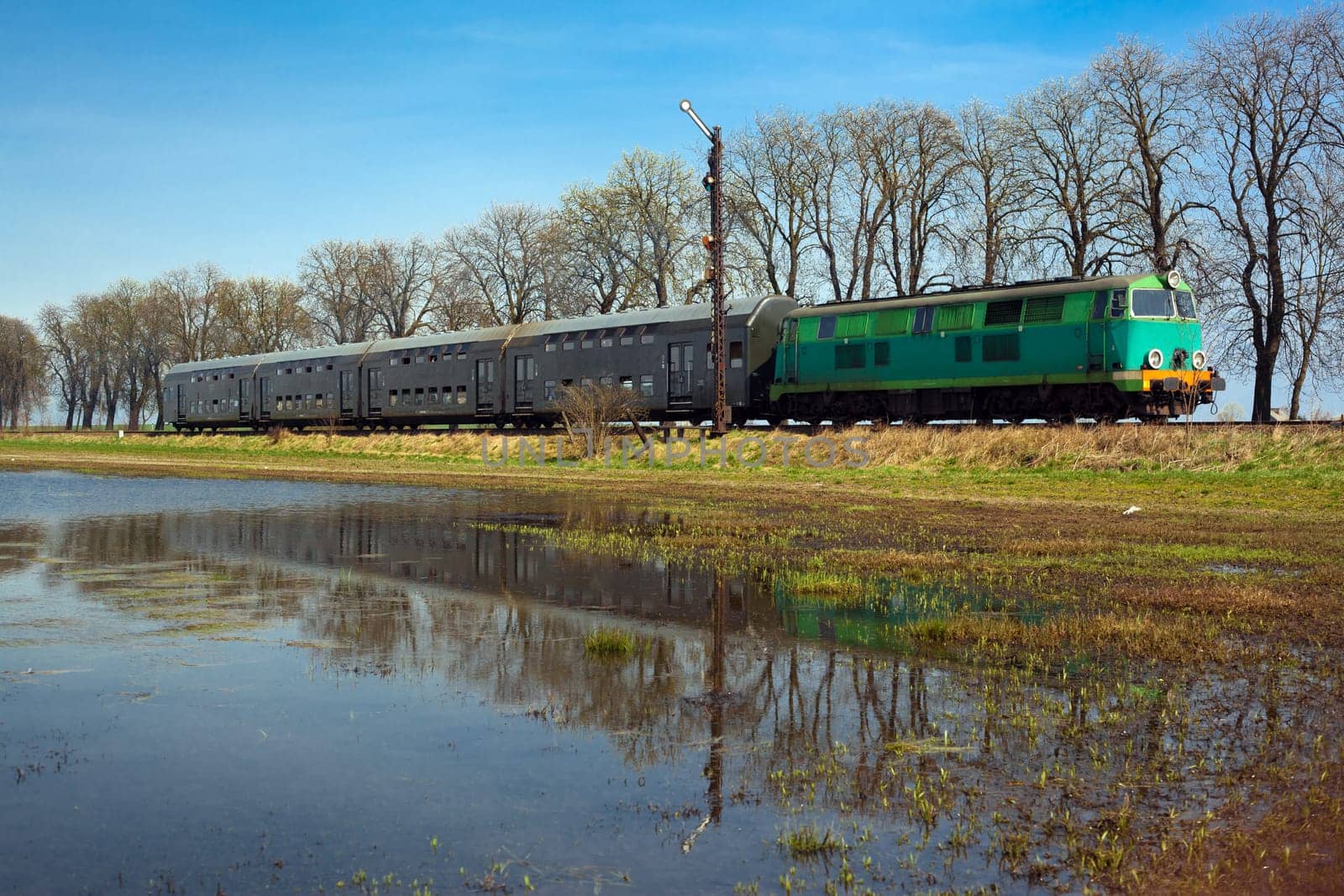 Passenger train hauled by the diesel locomotive passing the sunny landscape