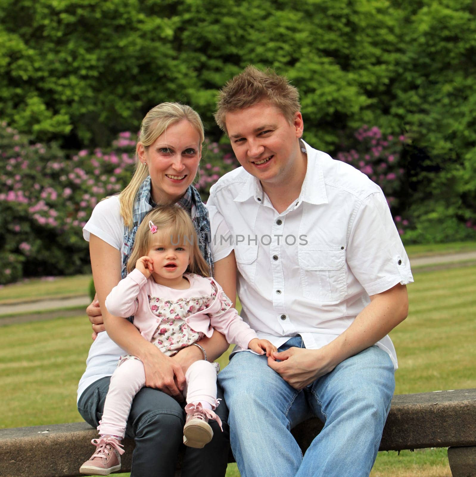 Young family with child in the park. The family sits on a park bench and laughs squarely