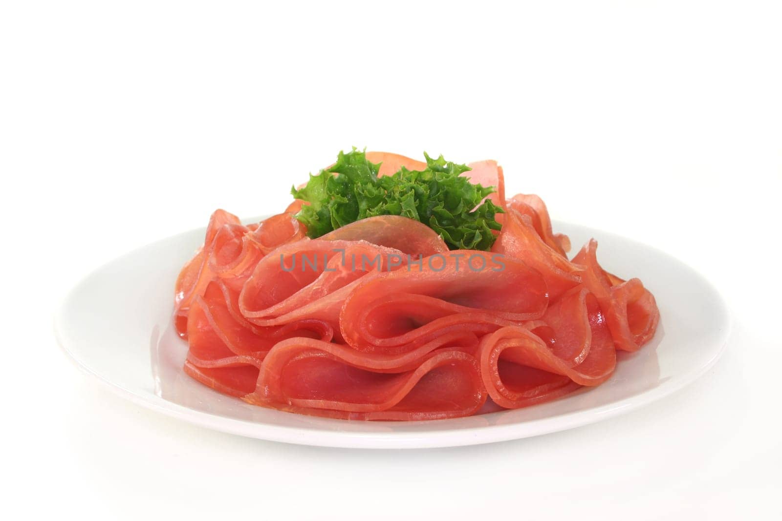 Salmon ham and a lettuce leaf on a white plate