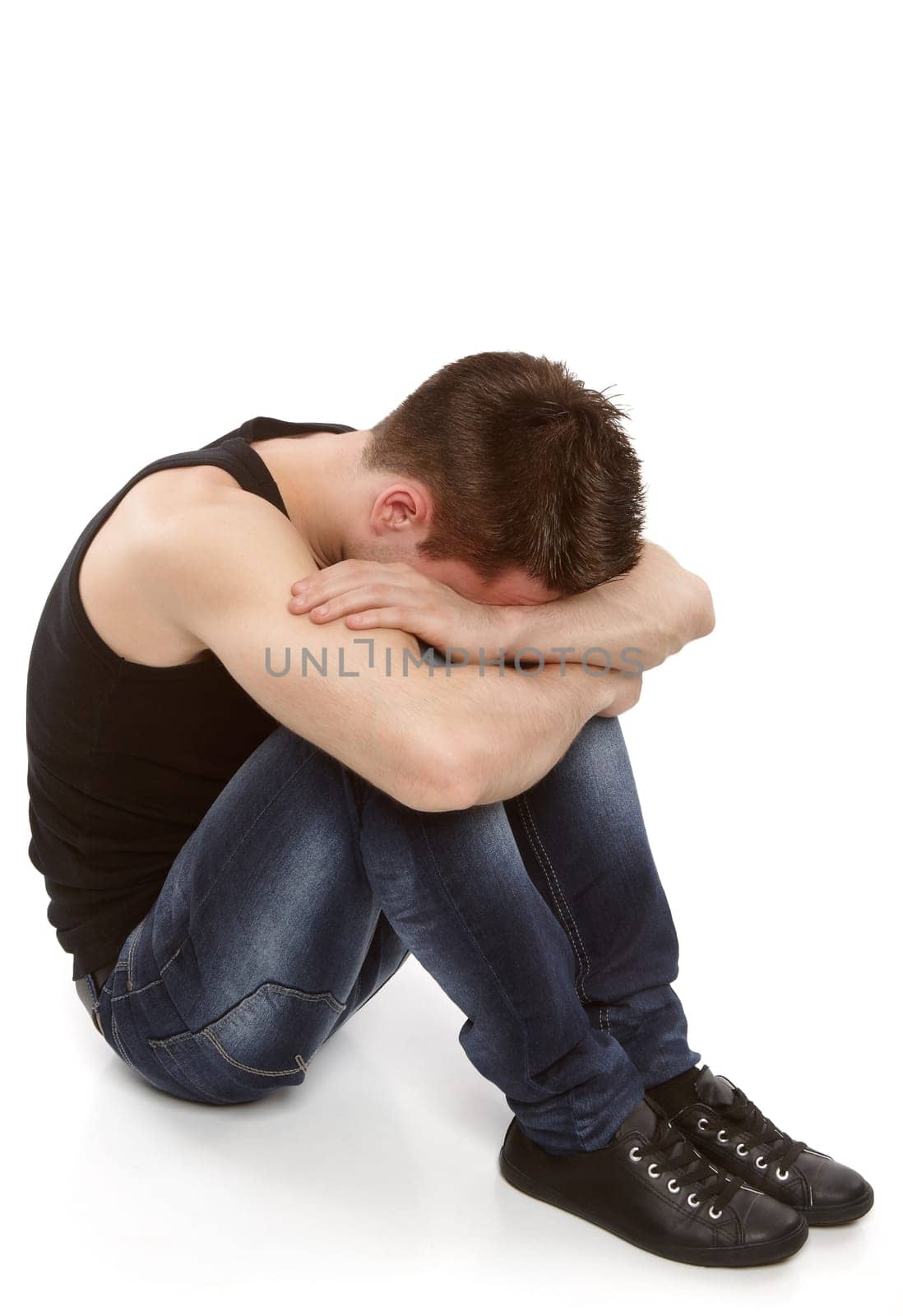 Young man thinking and hiding his face between his knees