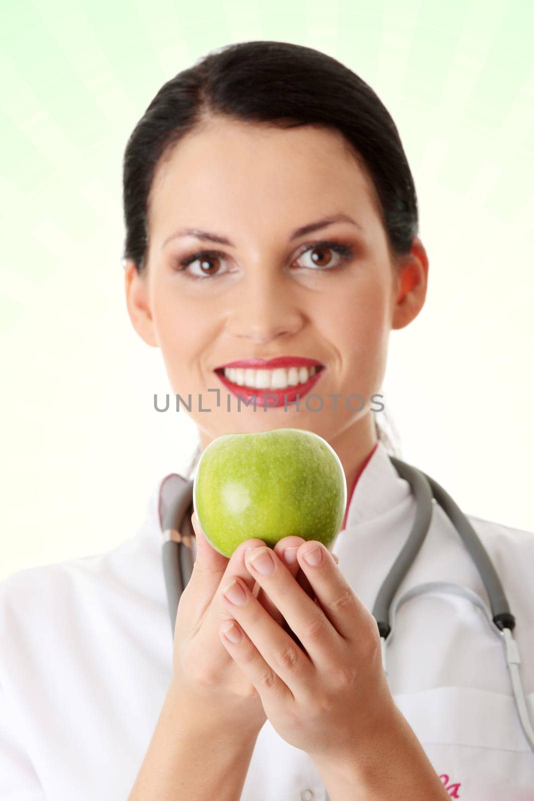 Healthy eating or lifestyle concept. Smiling woman doctor with a green apple.