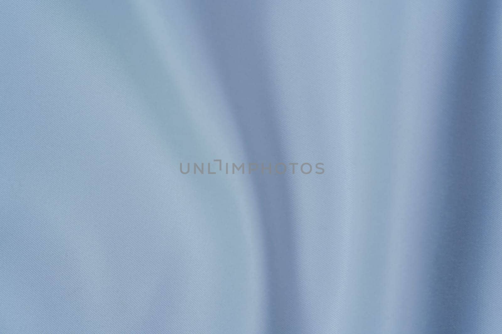 Close-up of soft white fabric with gentle folds creating a swirl pattern, perfect for backgrounds, textures, and design projects.