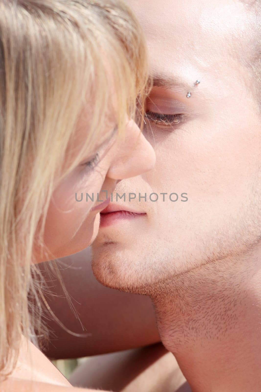 A beautiful couple sitting an kissing in wheat field